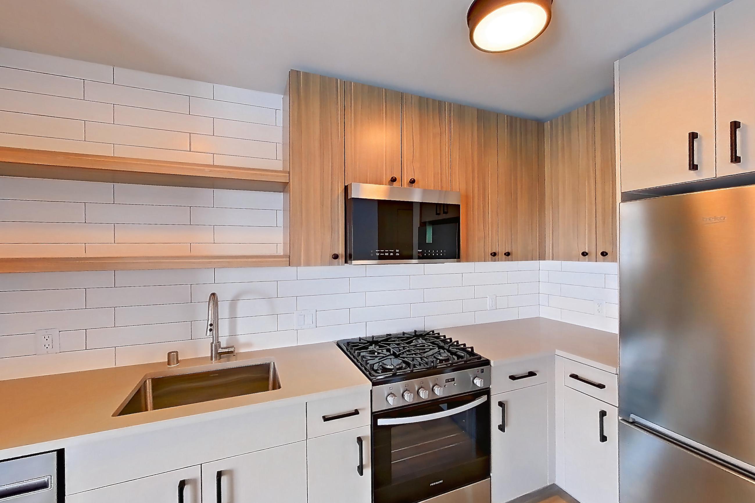 Kitchen with dishwasher, gas range, light countertops, light wood-finish flooring, oven/range, refrigerator, and stainless steel appliances, Apartment 743 at The Myles