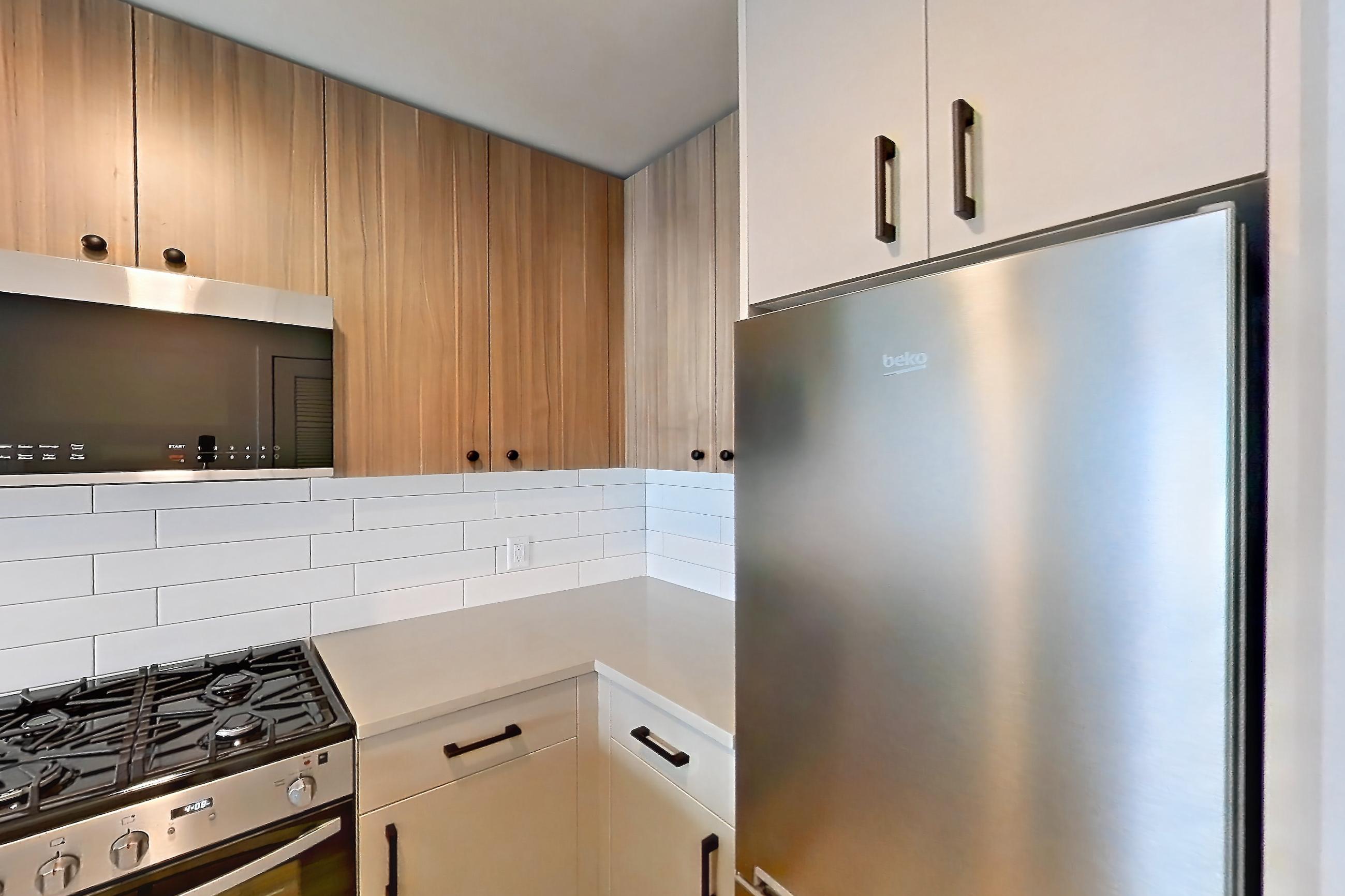 Kitchen with dishwasher, gas range, light countertops, light wood-finish flooring, oven/range, and stainless steel appliances, Apartment 744 at The Myles