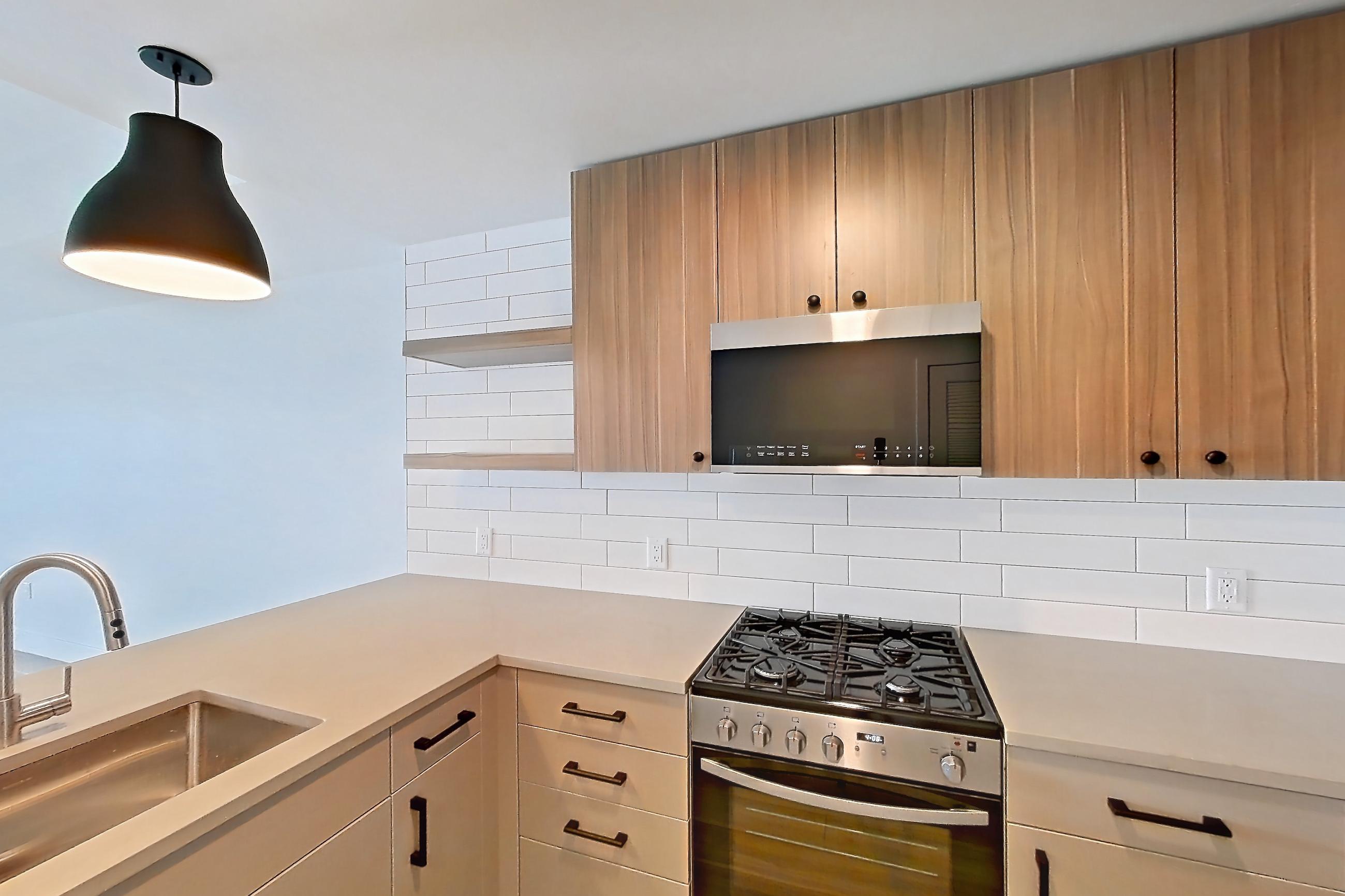Kitchen with dishwasher, gas range, light countertops, light wood-finish flooring, oven/range, and stainless steel appliances, Apartment 744 at The Myles