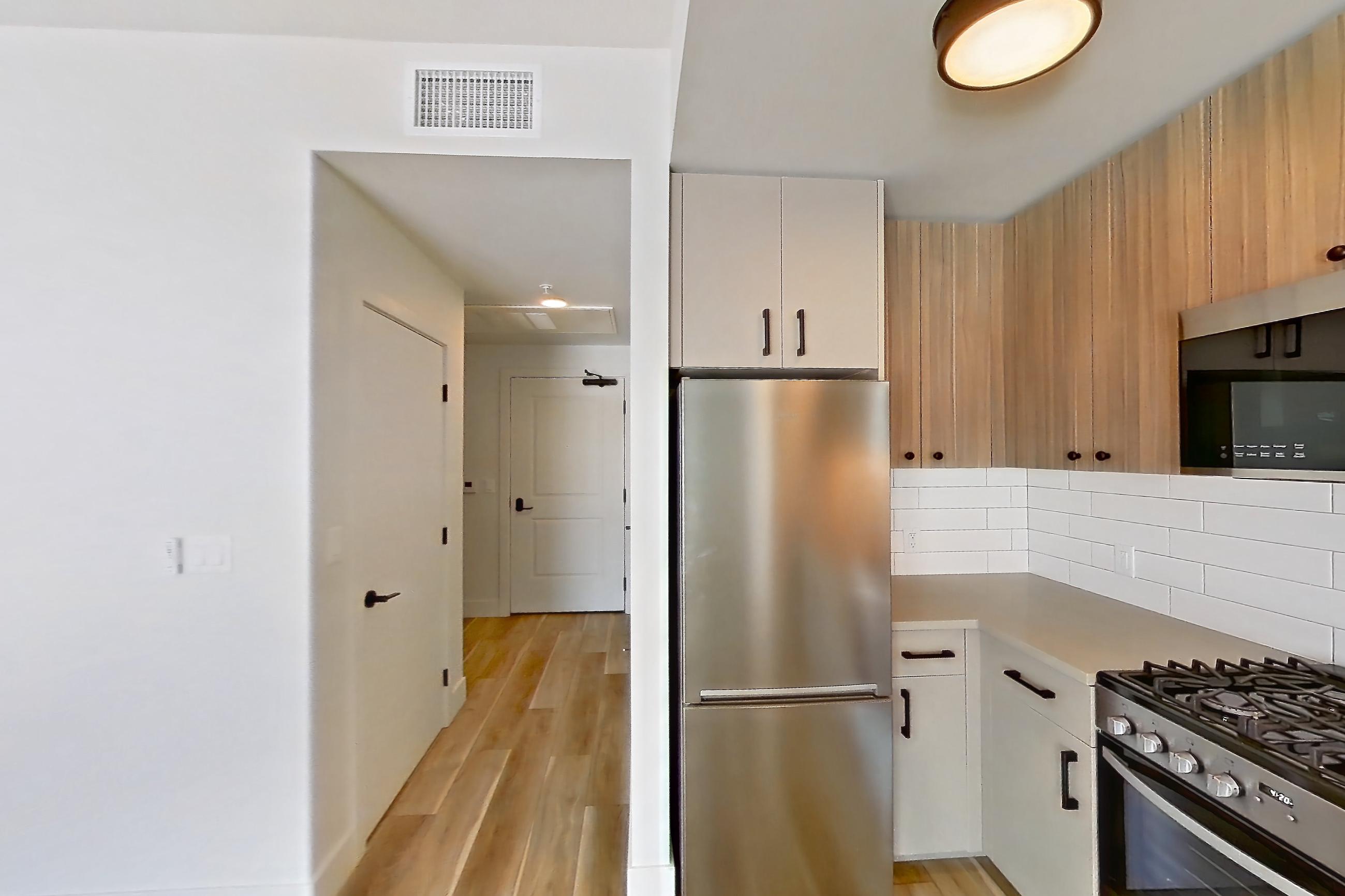 Kitchen with gas range, light countertops, light wood-finish flooring, oven/range, refrigerator, and stainless steel appliances, Apartment 745 at The Myles