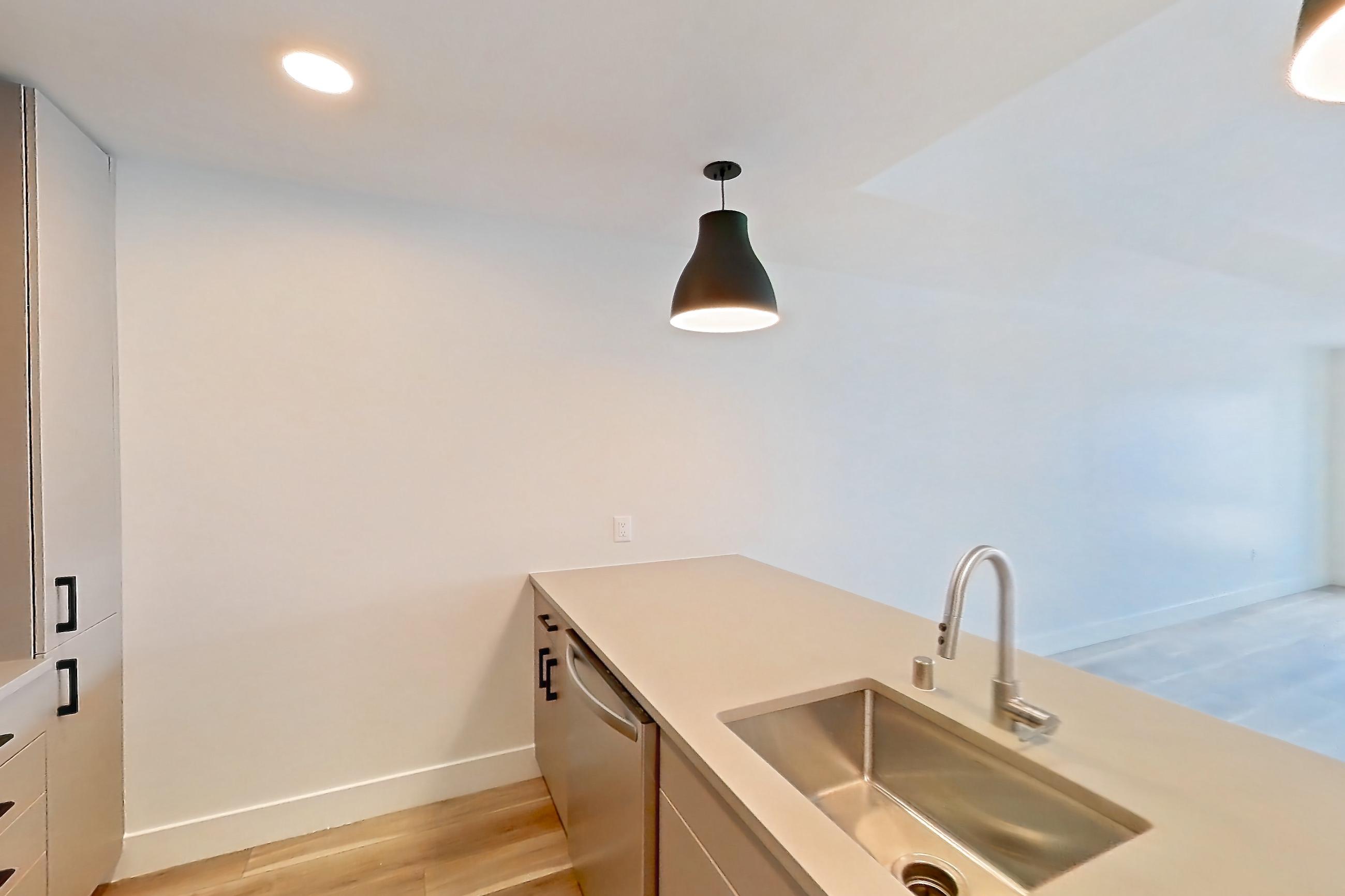 Kitchen with dishwasher, gas range, light countertops, light wood-finish flooring, microwave, oven/range, and stainless steel appliances, Apartment 746 at The Myles