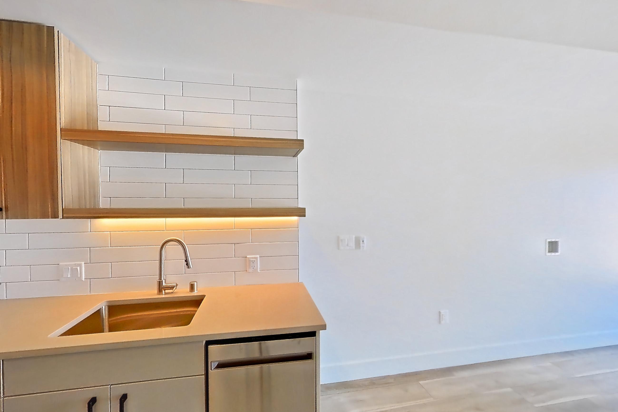 Kitchen with dishwasher, gas range, light countertops, light wood-finish flooring, oven/range, refrigerator, and stainless steel appliances, Apartment 751 at The Myles