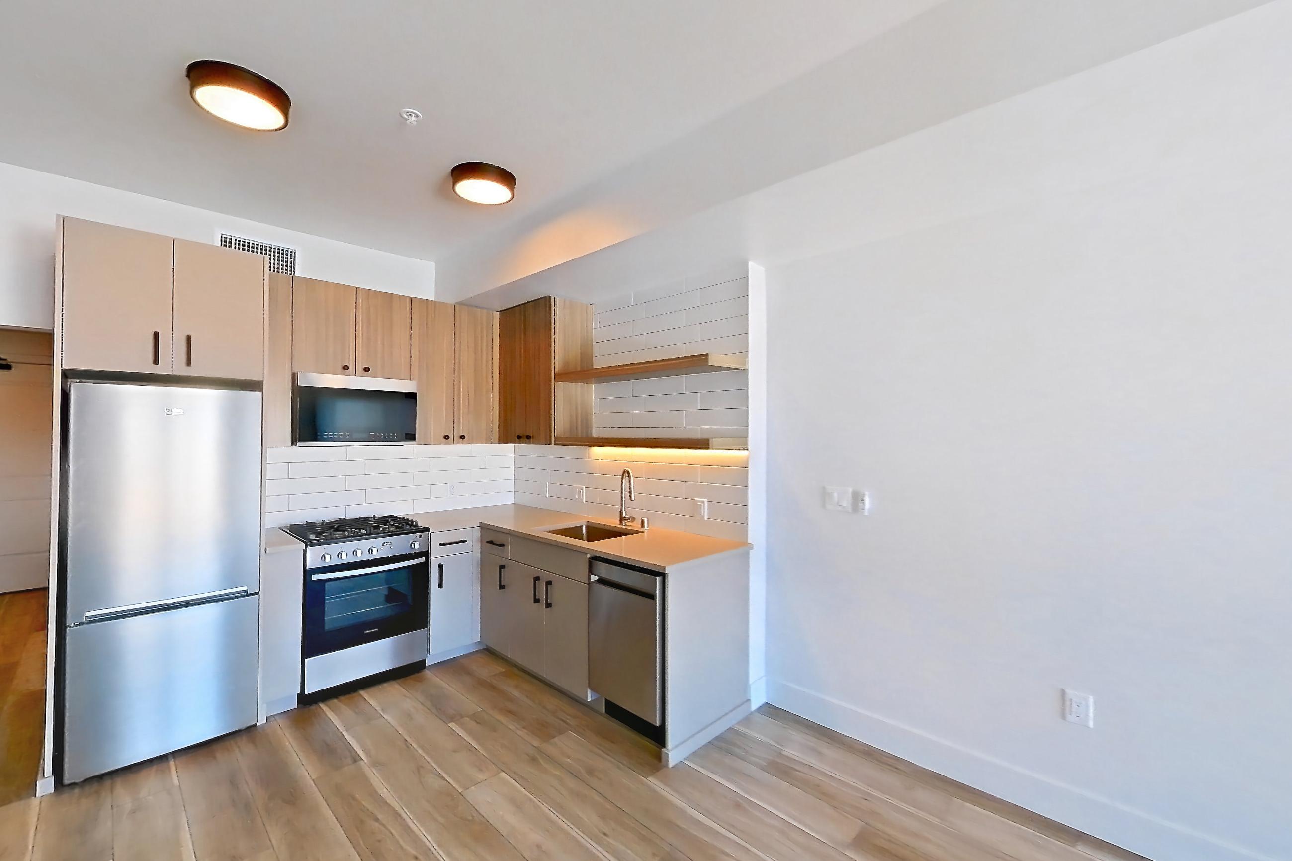 Living space with dishwasher, light countertops, light wood-finish flooring, and stainless steel appliances, Apartment 751 at The Myles