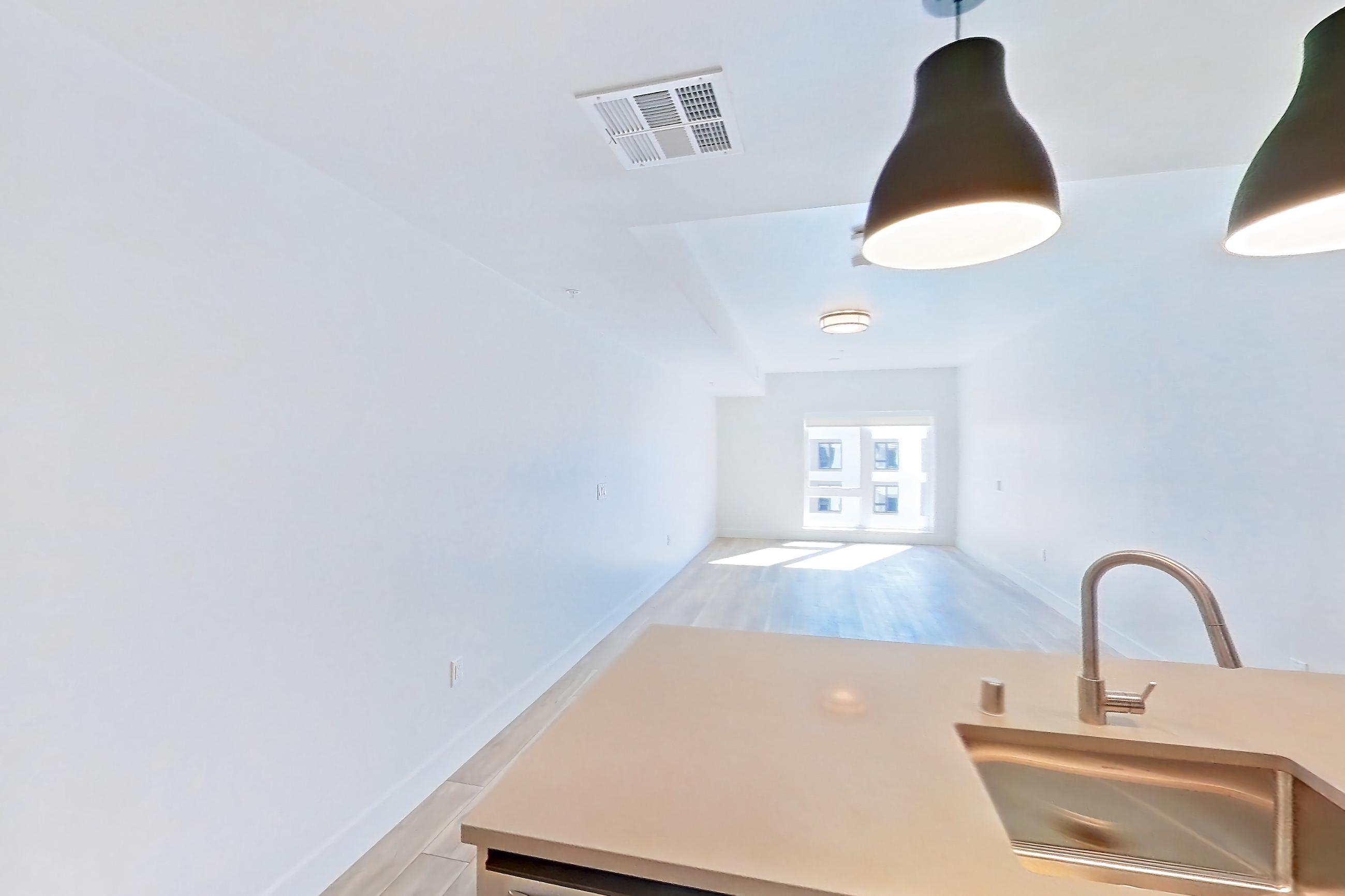 Kitchen with dishwasher, gas range, light countertops, light wood-finish flooring, microwave, oven/range, refrigerator, and stainless steel appliances, Apartment 752 at The Myles