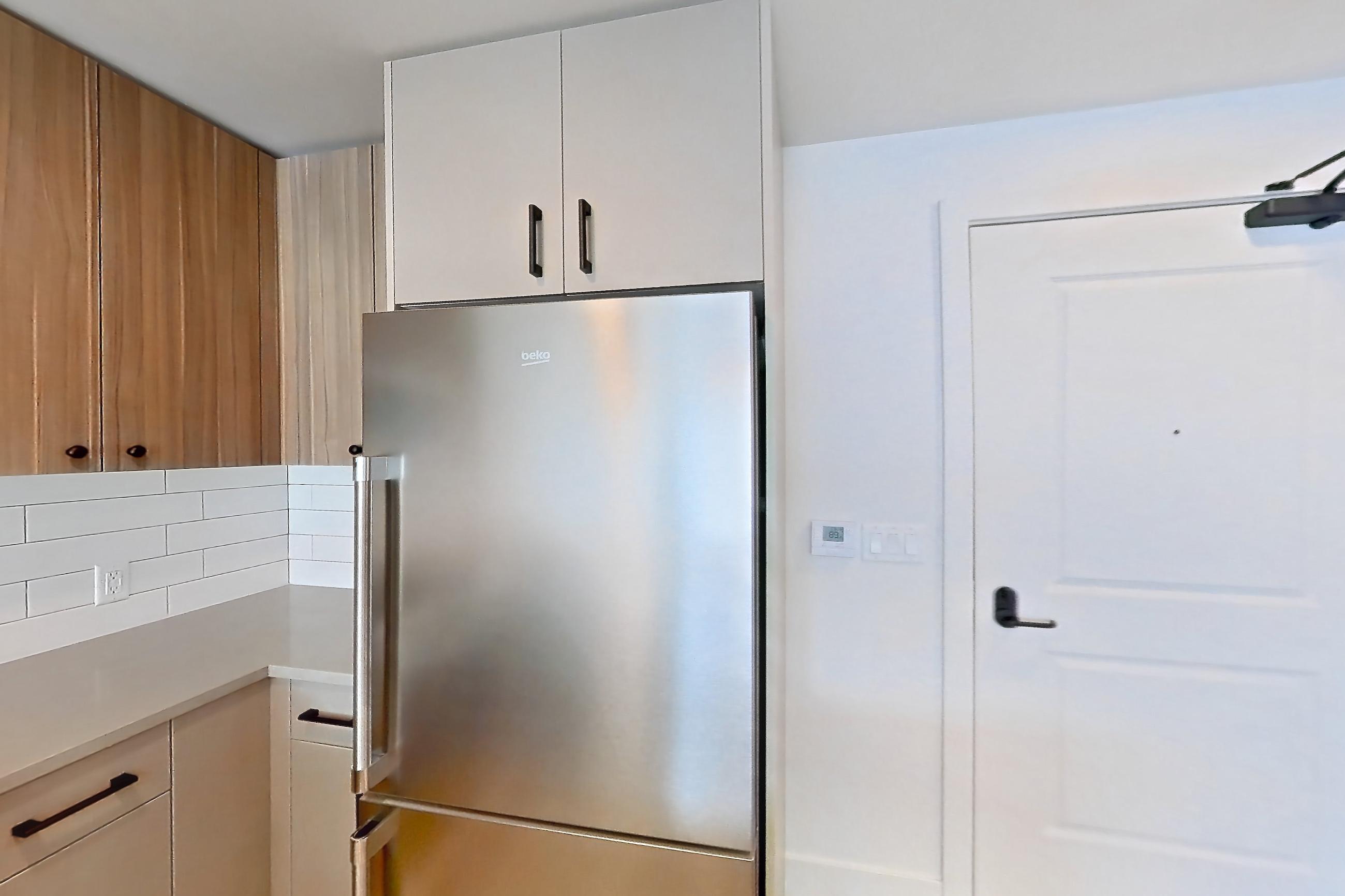 Kitchen with dishwasher, gas range, light countertops, light wood-finish flooring, microwave, oven/range, refrigerator, and stainless steel appliances, Apartment 752 at The Myles