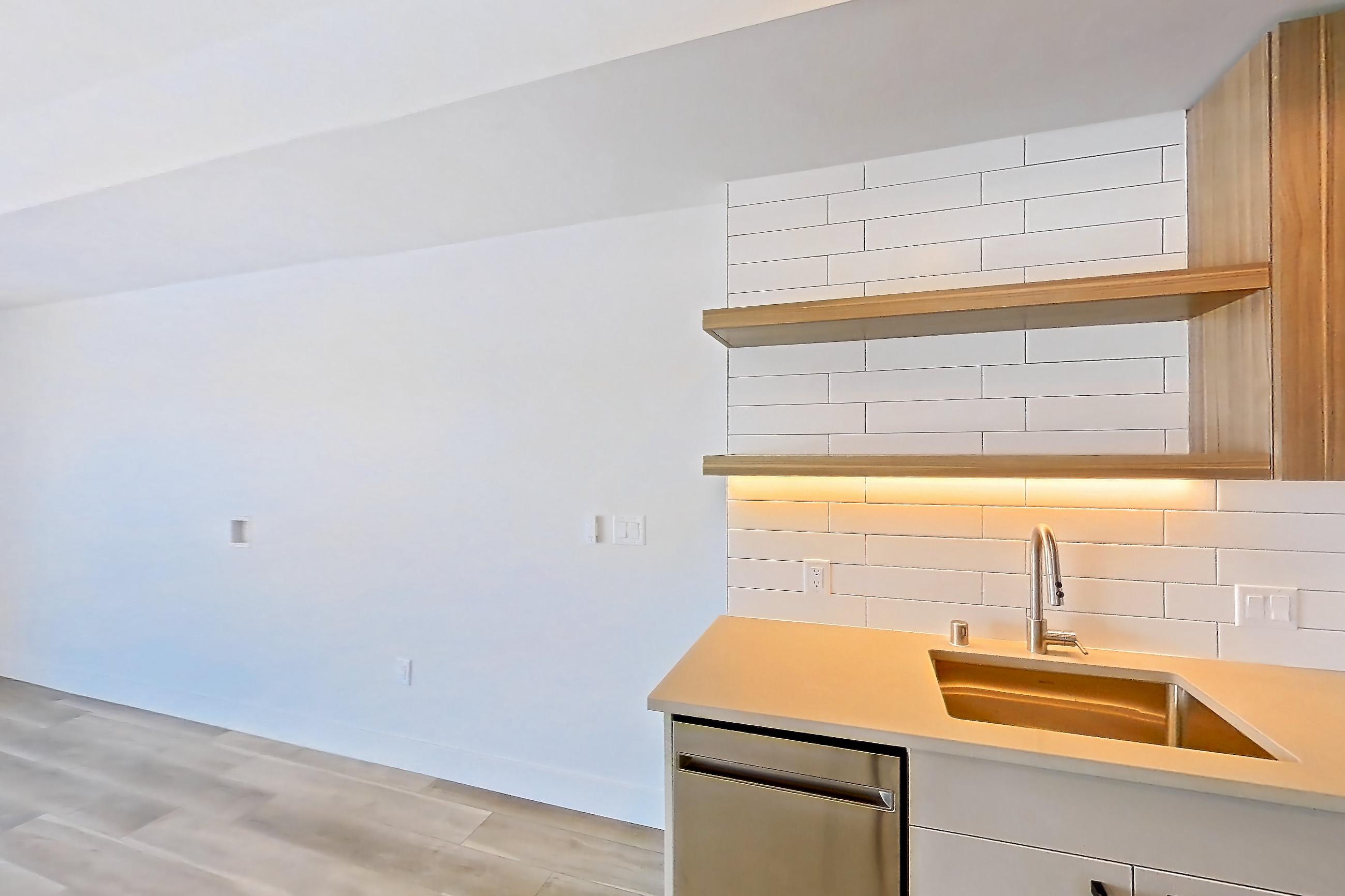 Kitchen with dishwasher, gas range, light countertops, light wood-finish flooring, oven/range, refrigerator, and stainless steel appliances, Apartment 753 at The Myles