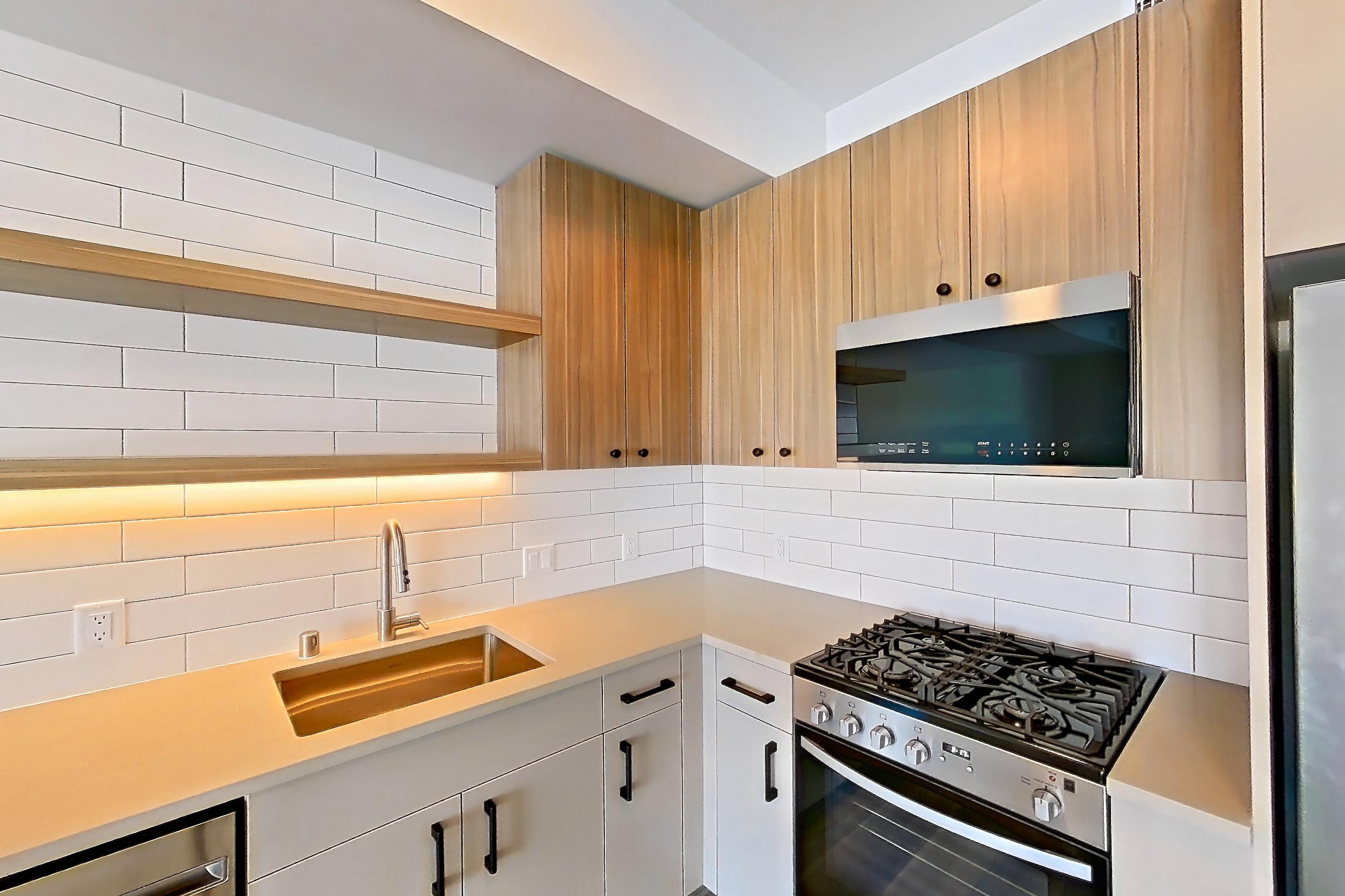 Kitchen with dishwasher, gas range, light countertops, light wood-finish flooring, oven/range, refrigerator, and stainless steel appliances, Apartment 753 at The Myles