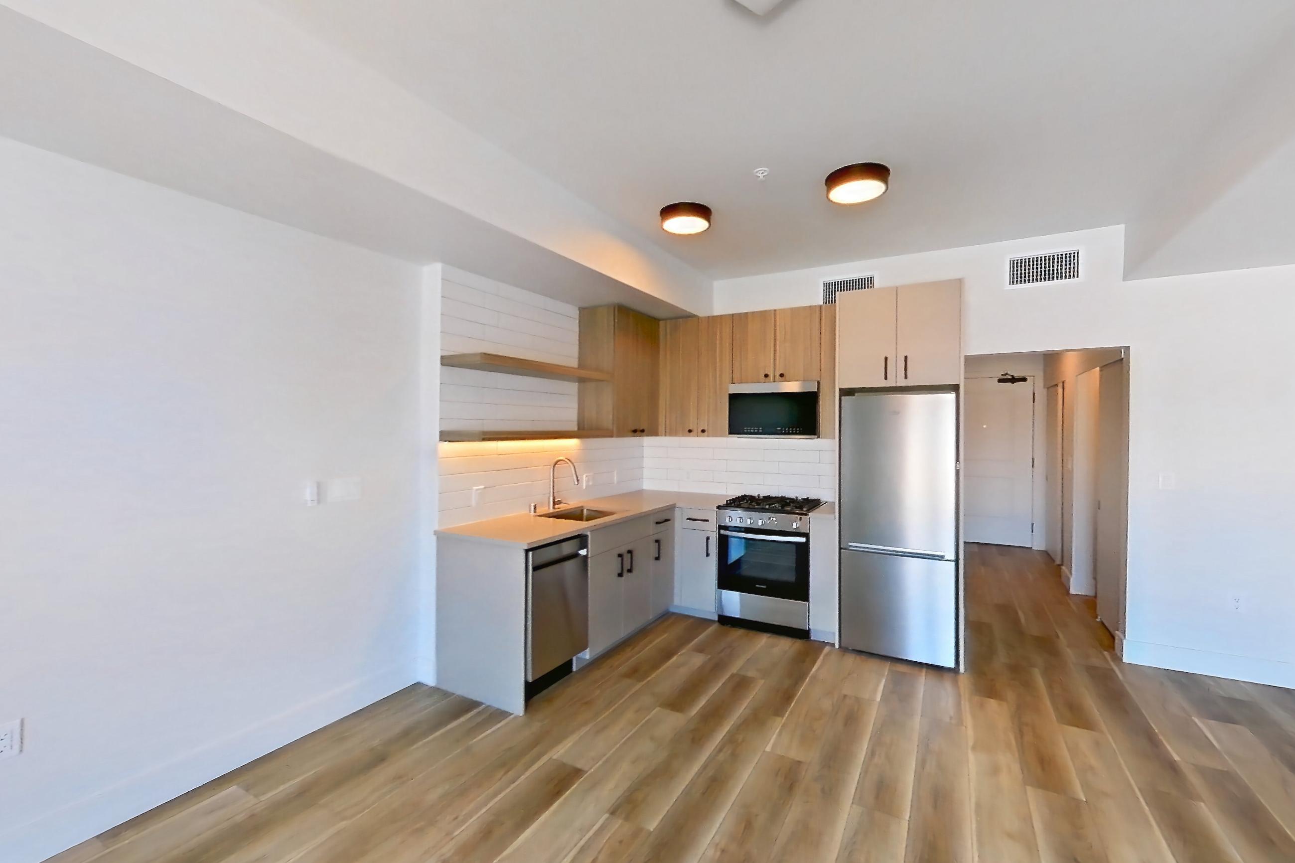 Living space with dishwasher, gas range, light countertops, light wood-finish flooring, oven/range, and stainless steel appliances, Apartment 753 at The Myles