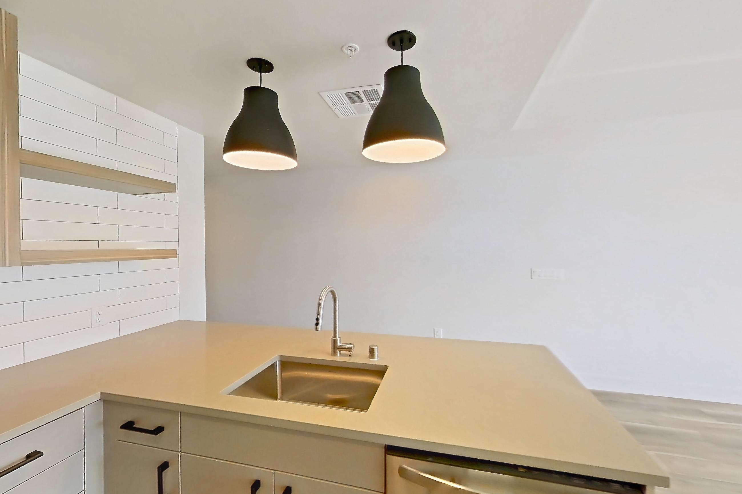Kitchen with dishwasher, gas range, light countertops, light wood-finish flooring, microwave, oven/range, refrigerator, and stainless steel appliances, Apartment 754 at The Myles