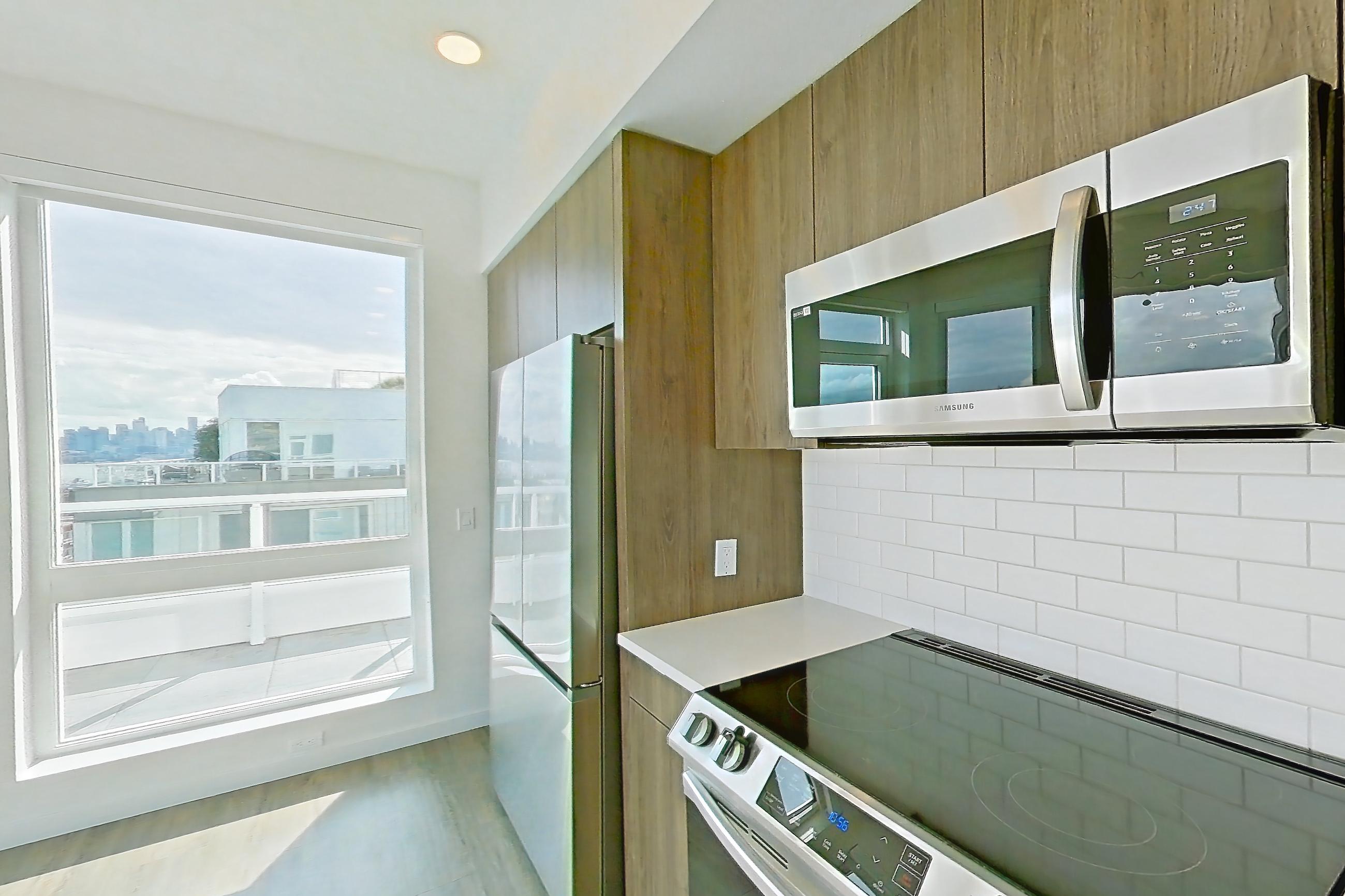 Kitchen with dishwasher, electric range, light countertops, light wood-finish flooring, microwave, mini-split AC, oven/range, refrigerator, and stainless steel appliances, Apartment 835 at The Cline
