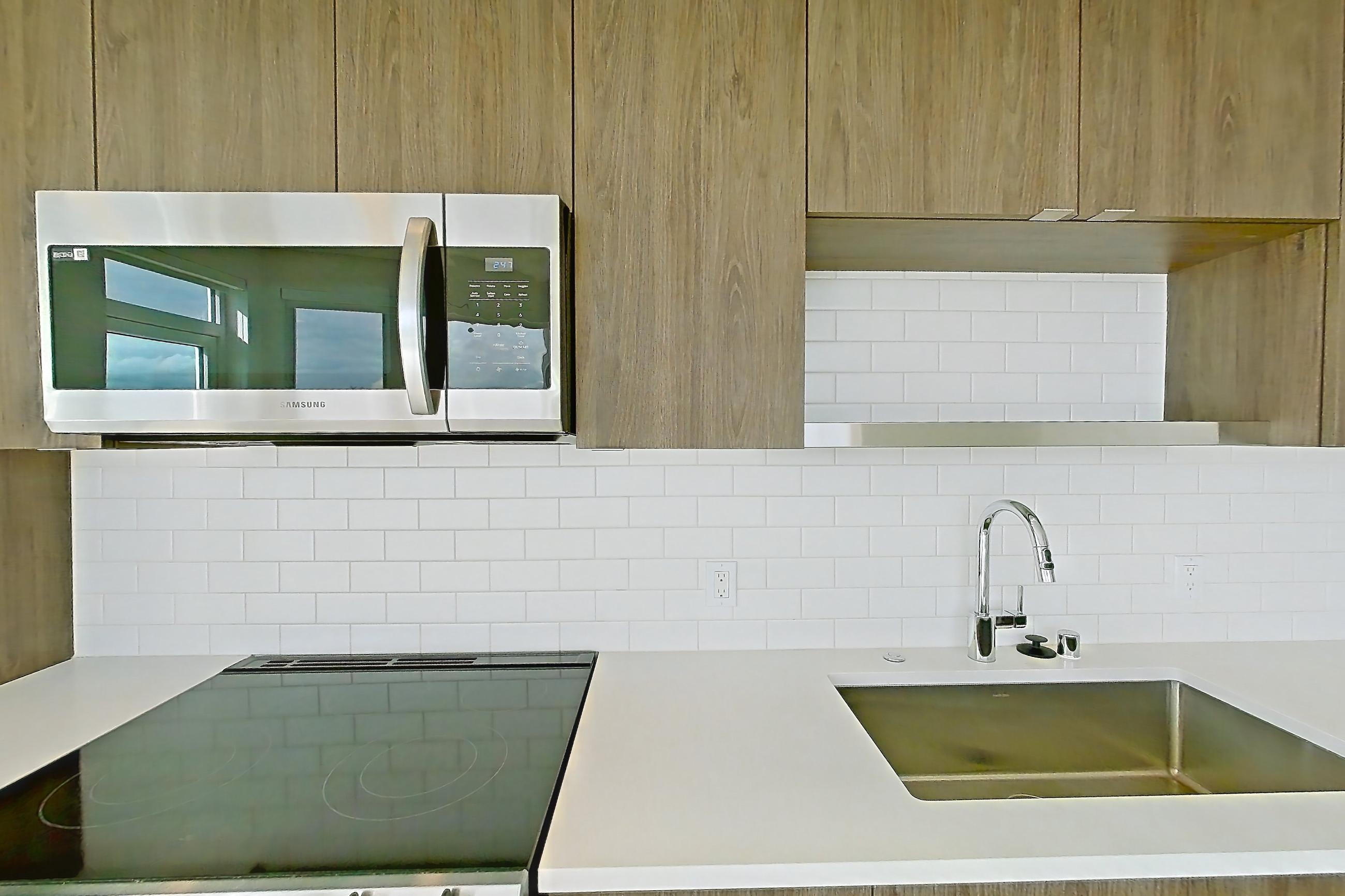 Kitchen with dishwasher, electric range, light countertops, light wood-finish flooring, microwave, mini-split AC, oven/range, refrigerator, and stainless steel appliances, Apartment 835 at The Cline