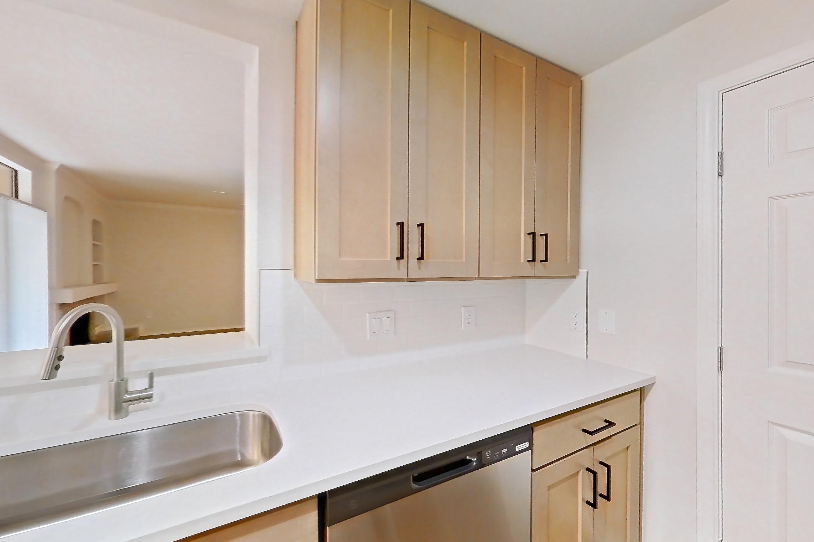 Kitchen with dishwasher, gas range, light countertops, light stone countertops, light wood-finish flooring, microwave, oven/range, and stainless steel appliances, Apartment 2001 at Marquis at Caprock Canyon