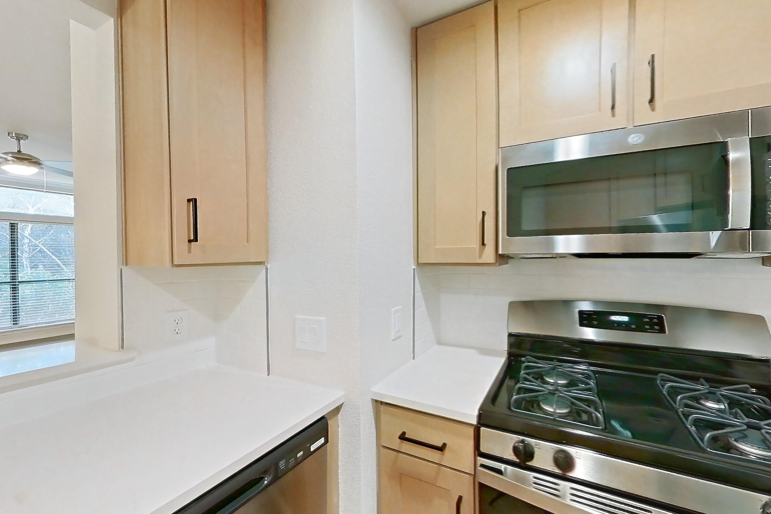 Kitchen with dishwasher, gas range, light butcher block countertops, light countertops, light wood-finish flooring, microwave, oven/range, refrigerator, and stainless steel appliances, Apartment 2701 at Marquis at Caprock Canyon