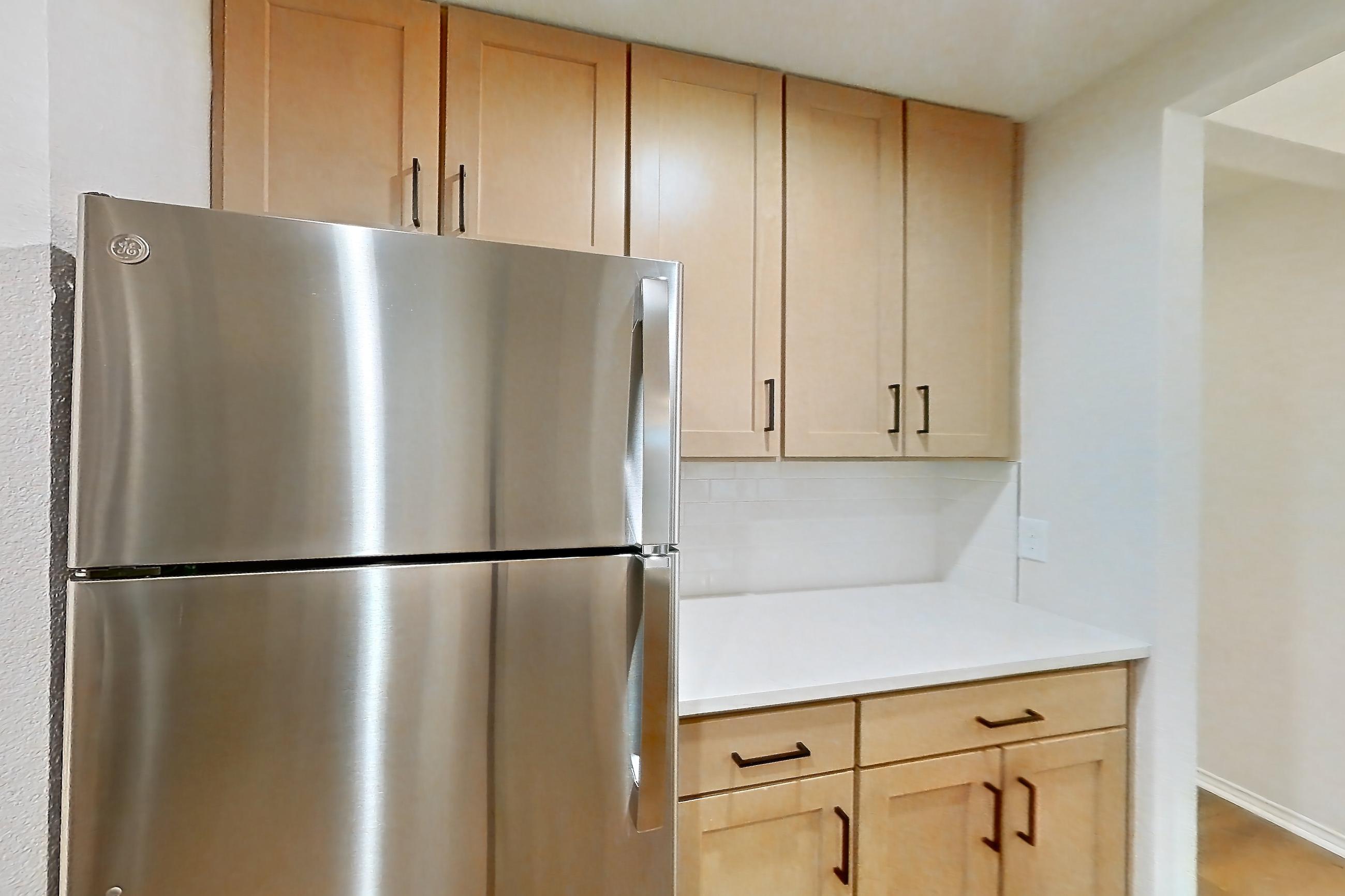 Kitchen with dishwasher, gas range, light butcher block countertops, light countertops, light wood-finish flooring, microwave, oven/range, refrigerator, and stainless steel appliances, Apartment 2701 at Marquis at Caprock Canyon