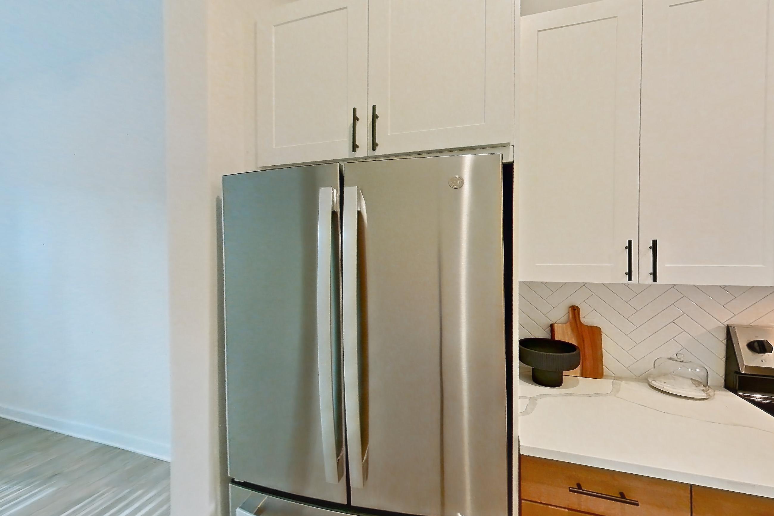 Kitchen with electric range, light countertops, light stone countertops, light wood-finish flooring, microwave, oven/range, refrigerator, and stainless steel appliances, Apartment 334 at The Rowe at Commonwealth