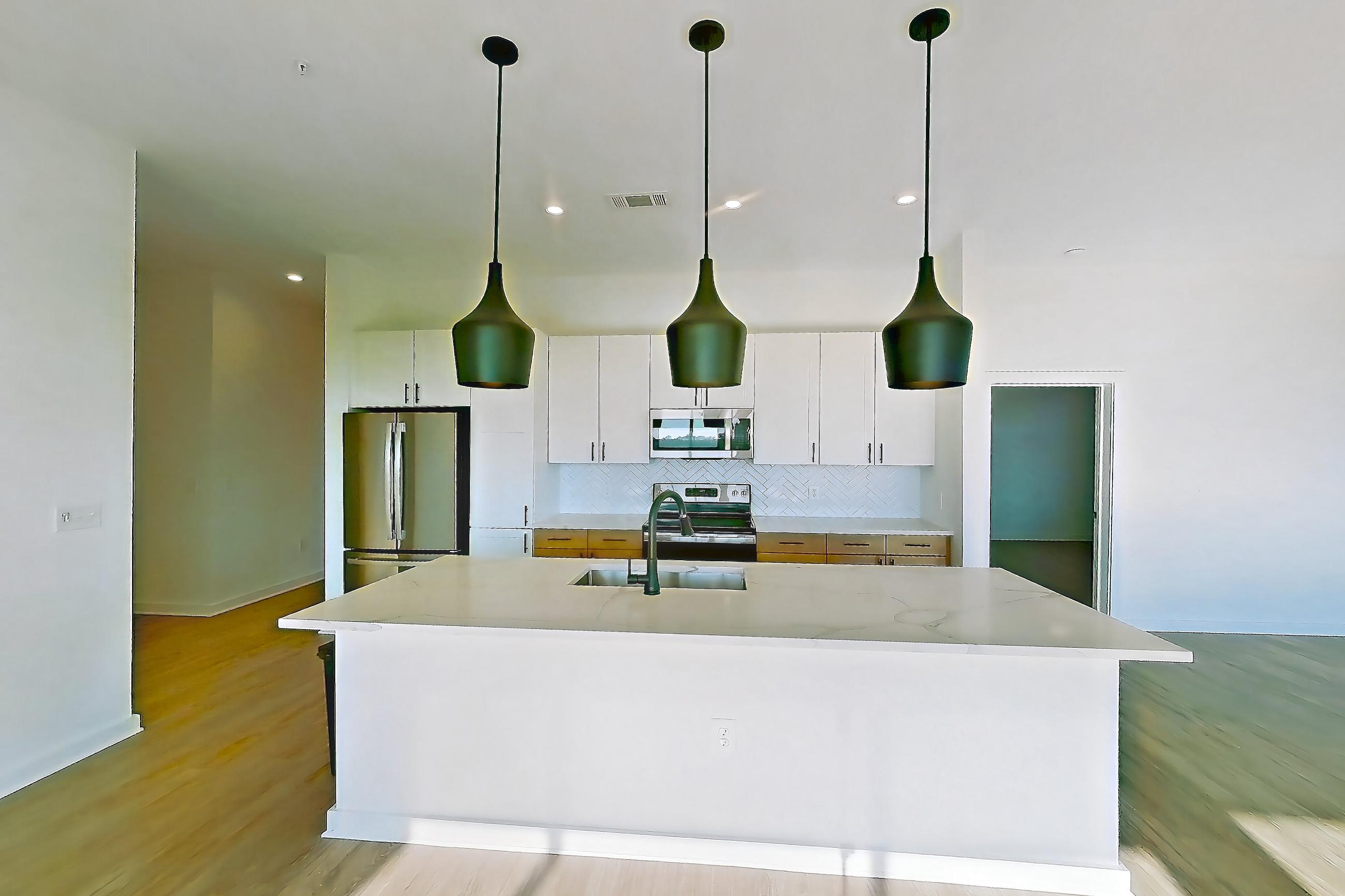 Living space with electric range, kitchen island, light countertops, light stone countertops, light wood-finish flooring, oven/range, refrigerator, and stainless steel appliances, Apartment 758 at The Rowe at Commonwealth