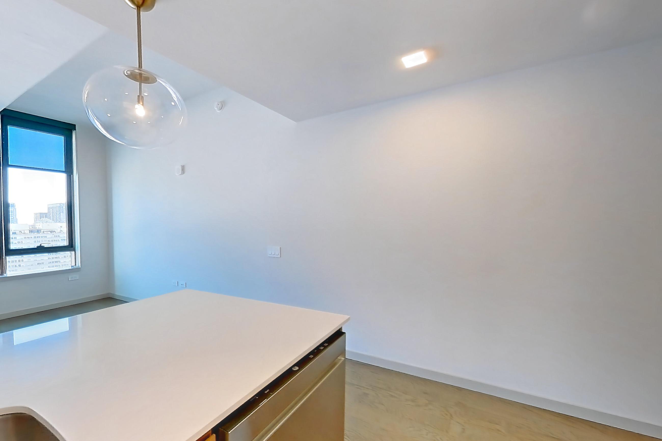 Kitchen with dishwasher, electric range, kitchen island, light countertops, light stone countertops, light wood-finish flooring, microwave, oven/range, refrigerator, stainless steel appliances, and water & ice dispenser, Apartment 2403 at 1909 Rittenhouse