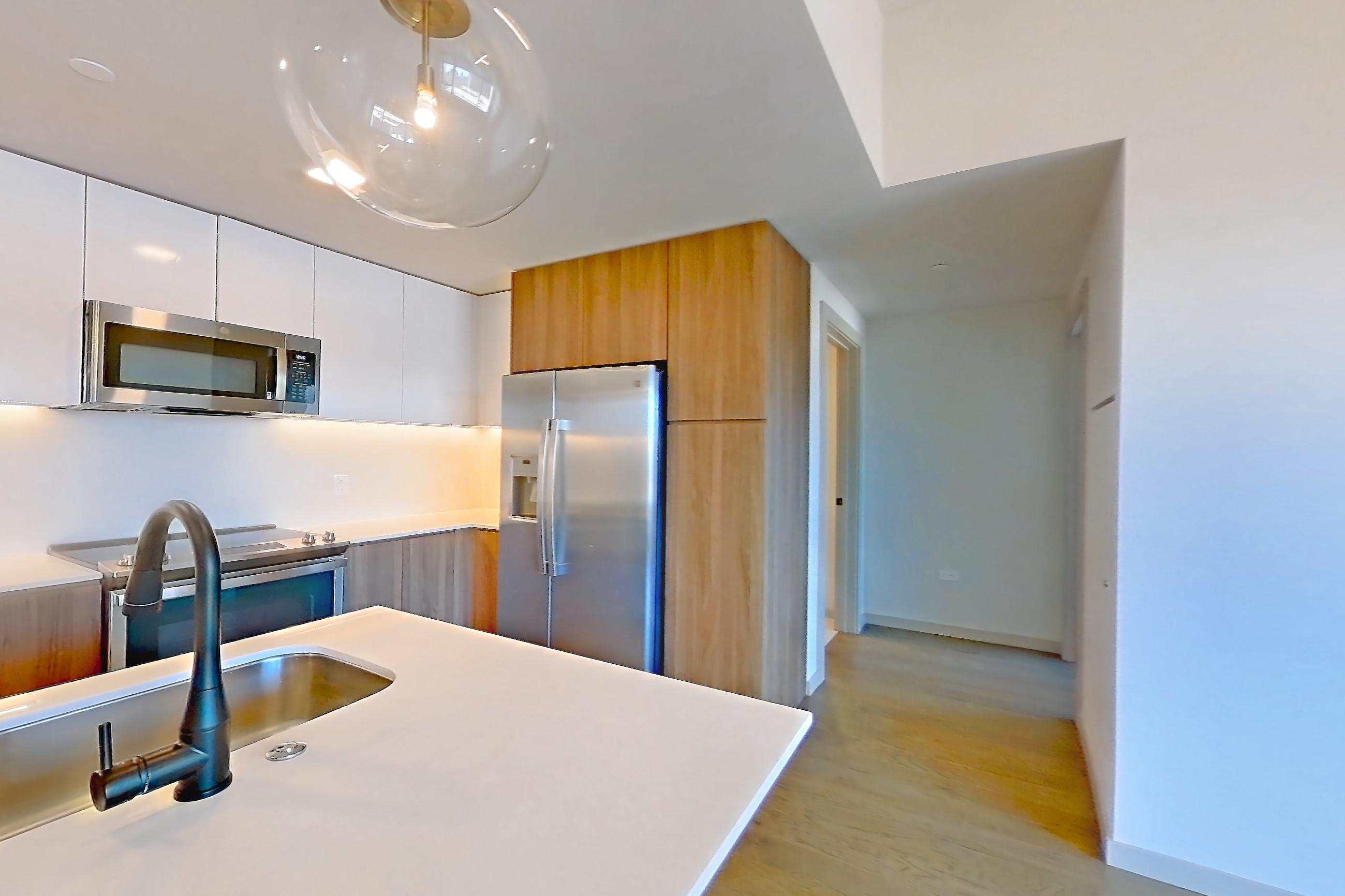 Living space with light wood-finish flooring, refrigerator, and stainless steel appliances, Apartment 2403 at 1909 Rittenhouse