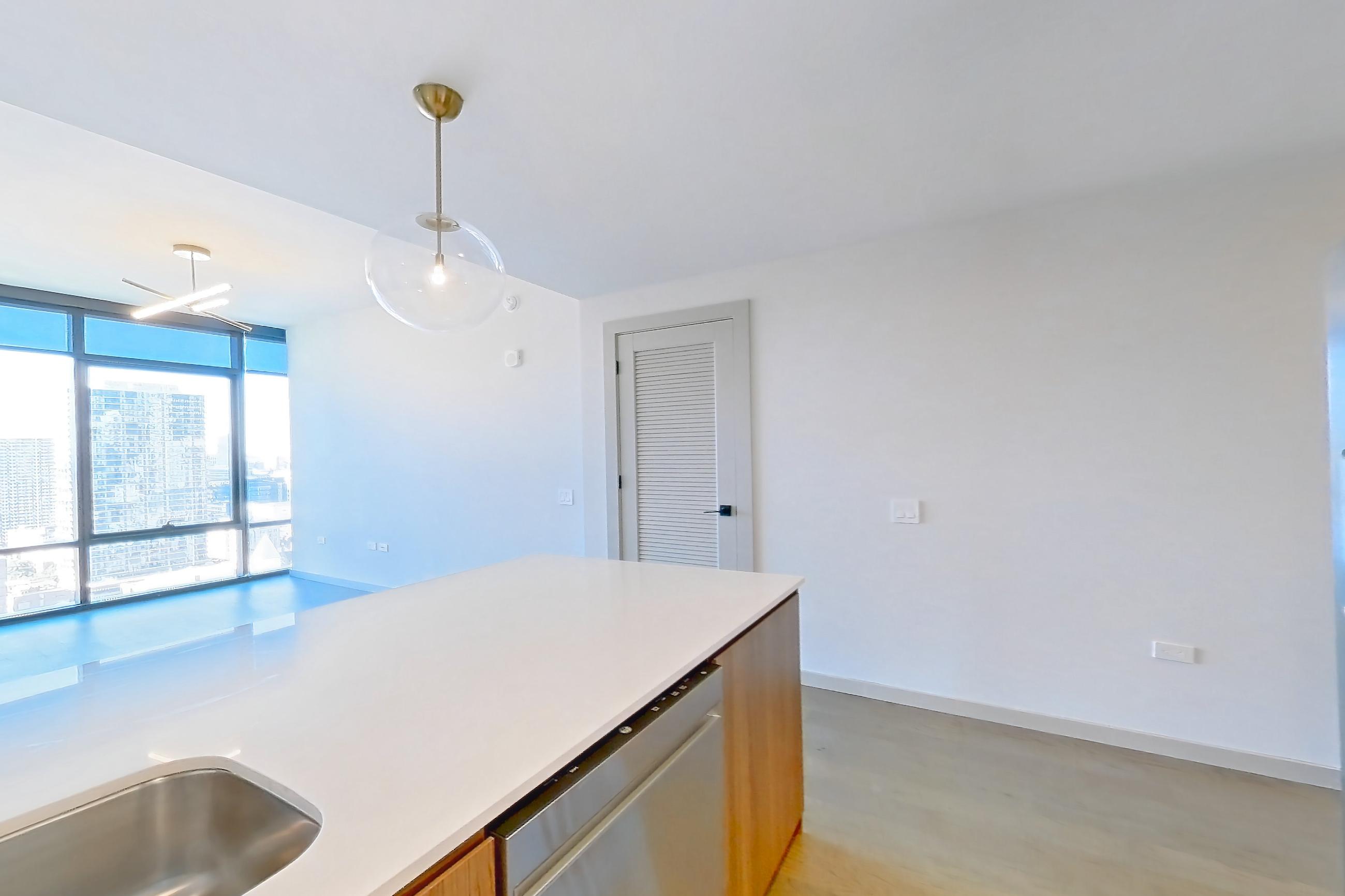 Kitchen with dishwasher, kitchen island, light countertops, light stone countertops, light wood-finish flooring, refrigerator, and stainless steel appliances, Apartment 2008 at 1909 Rittenhouse