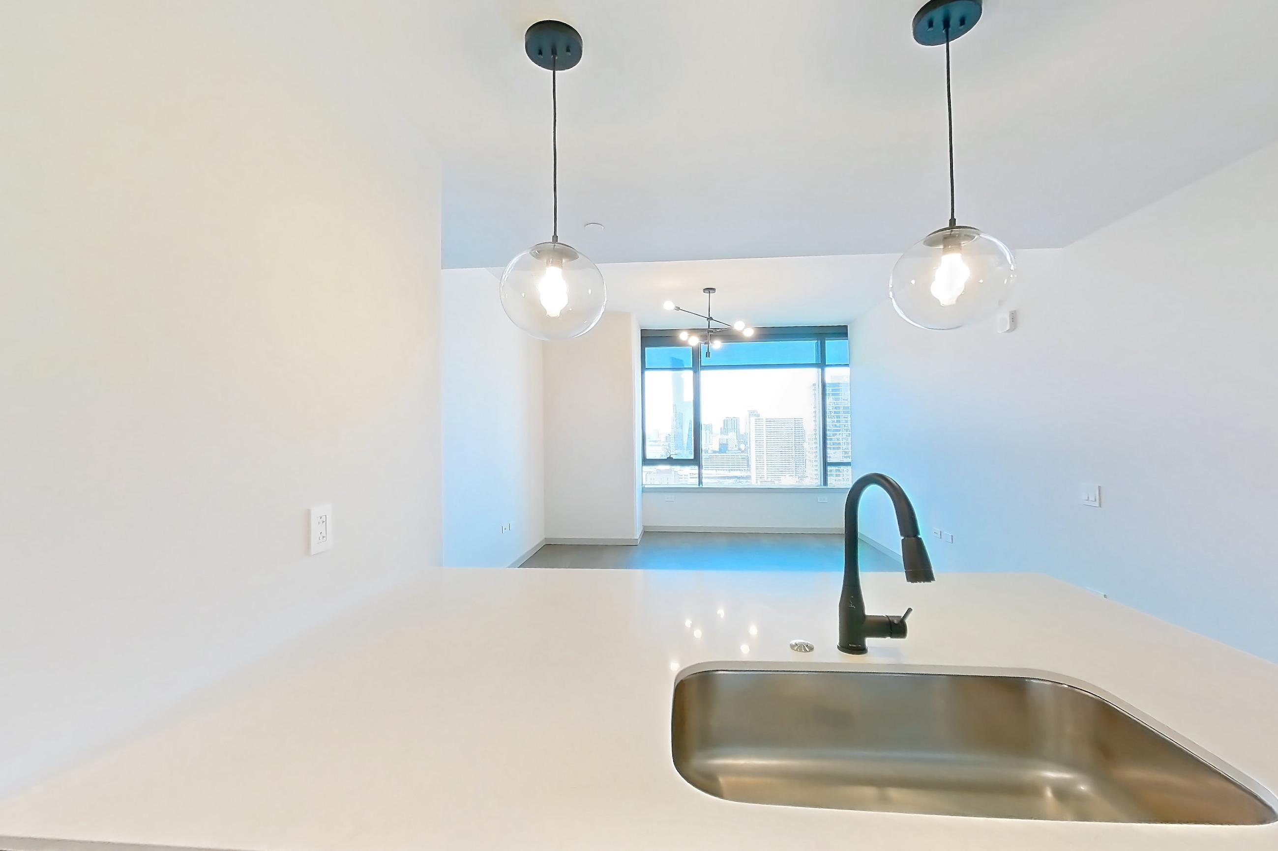 Kitchen with dishwasher, electric range, light countertops, light stone countertops, light wood-finish flooring, microwave, oven/range, and stainless steel appliances, Apartment 2006 at 1909 Rittenhouse