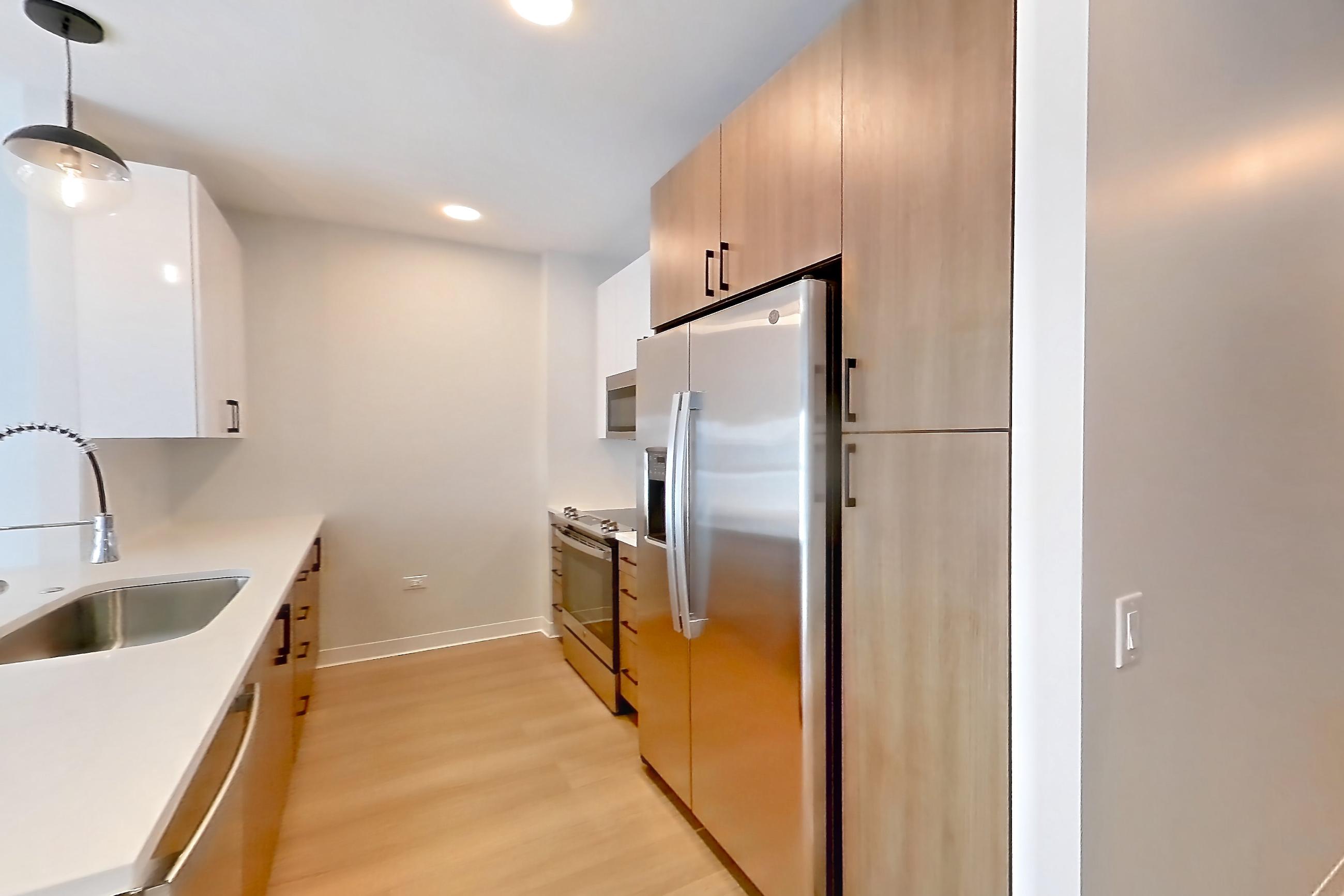 Living space with dishwasher, light stone countertops, light wood-finish flooring, oven/range, refrigerator, and stainless steel appliances, Apartment 1110 at The Alcott