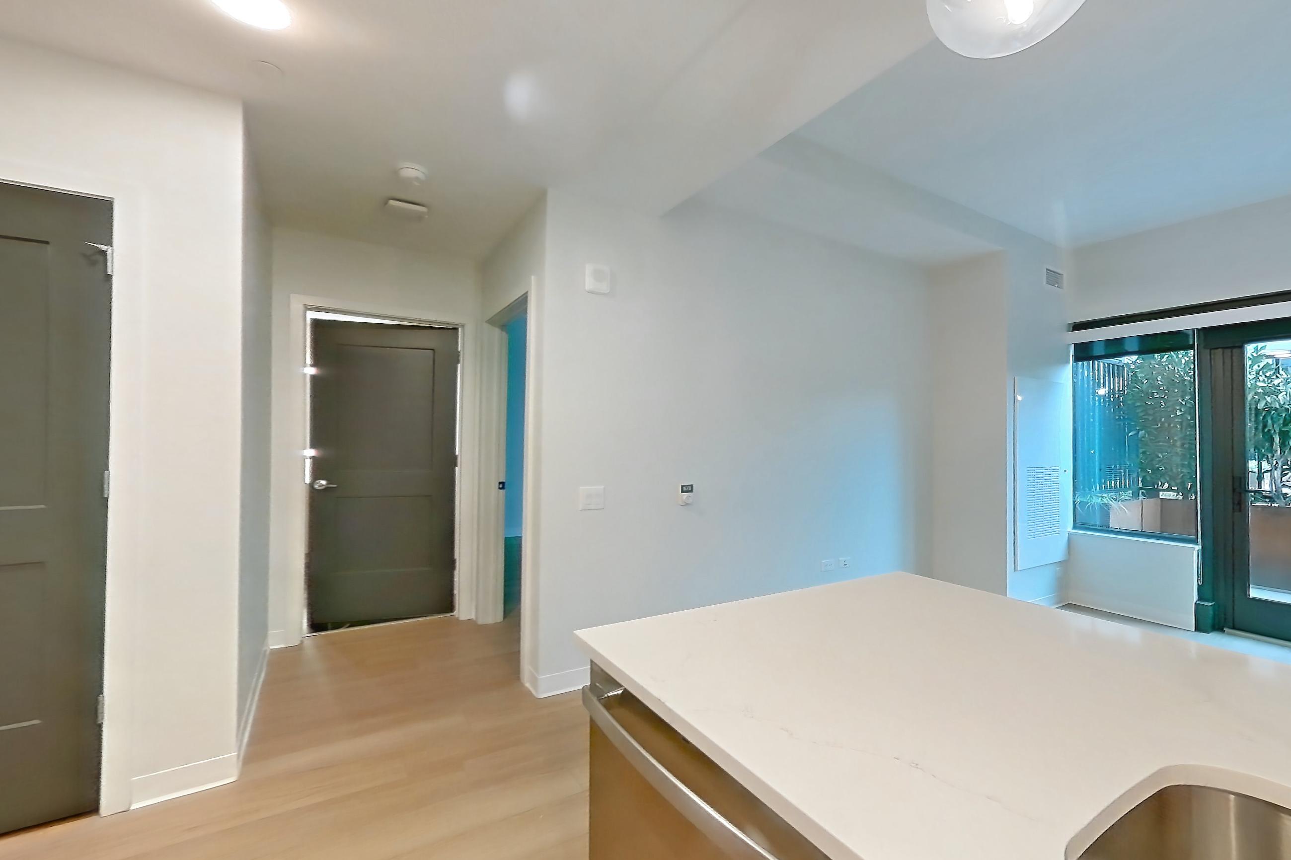 Kitchen with dishwasher, electric range, light countertops, light stone countertops, light wood-finish flooring, oven/range, and stainless steel appliances, Apartment 0210 at The Alcott
