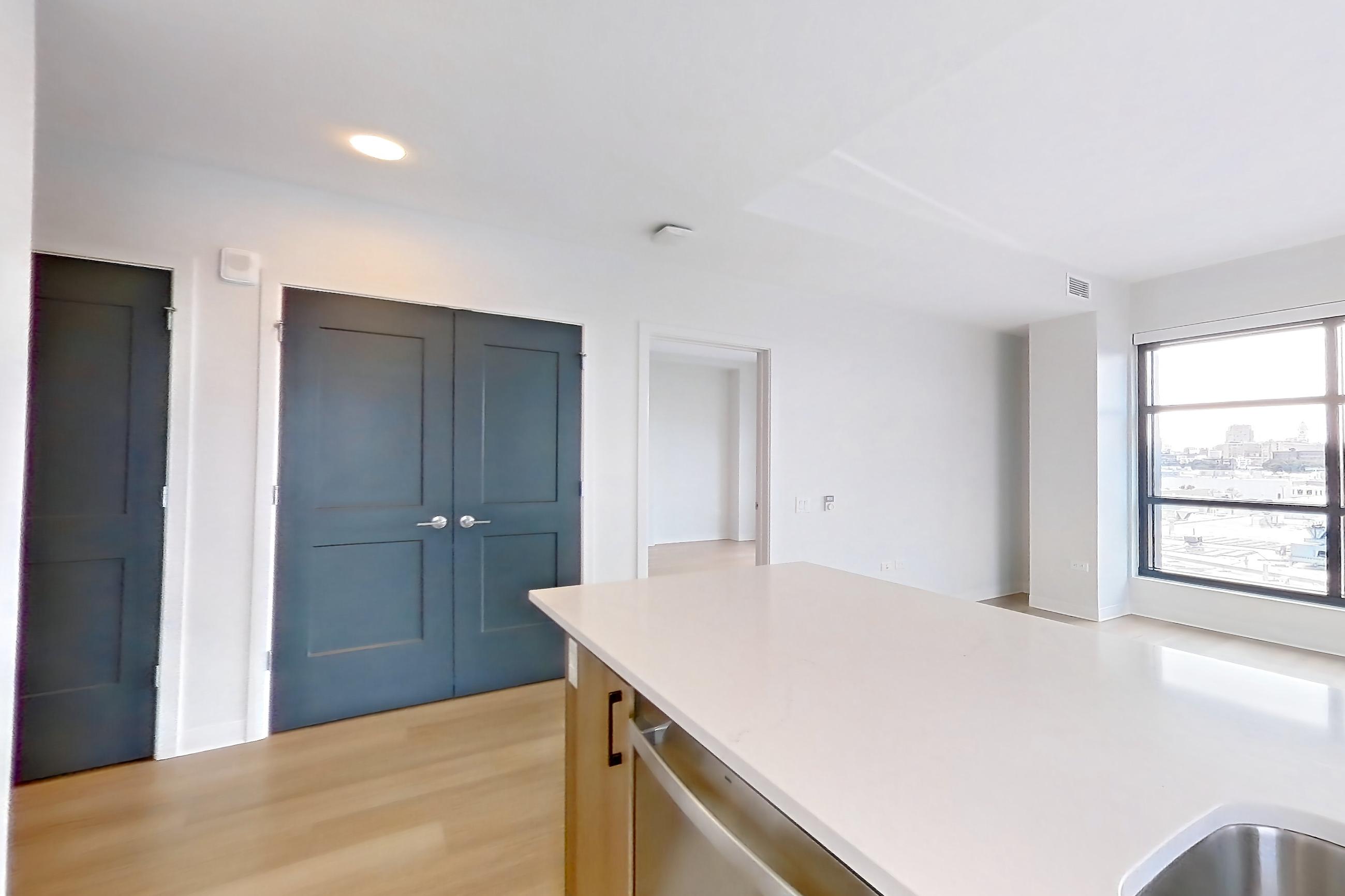 Kitchen with dishwasher, electric range, kitchen island, light stone countertops, light wood-finish flooring, oven/range, and stainless steel appliances, Apartment 0615 at The Alcott