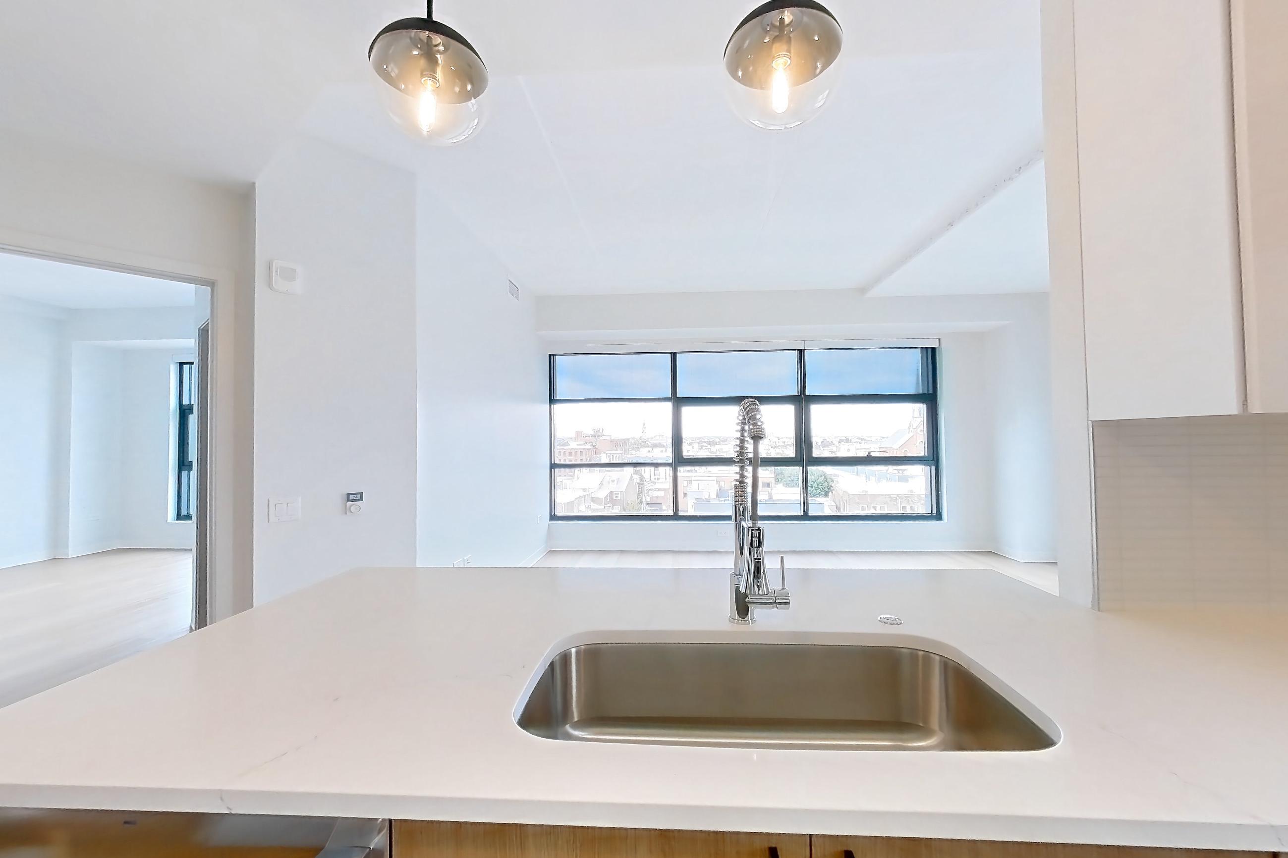 Kitchen with dishwasher, electric range, light countertops, light stone countertops, light wood-finish flooring, oven/range, refrigerator, stainless steel appliances, and water & ice dispenser, Apartment 0729 at The Alcott