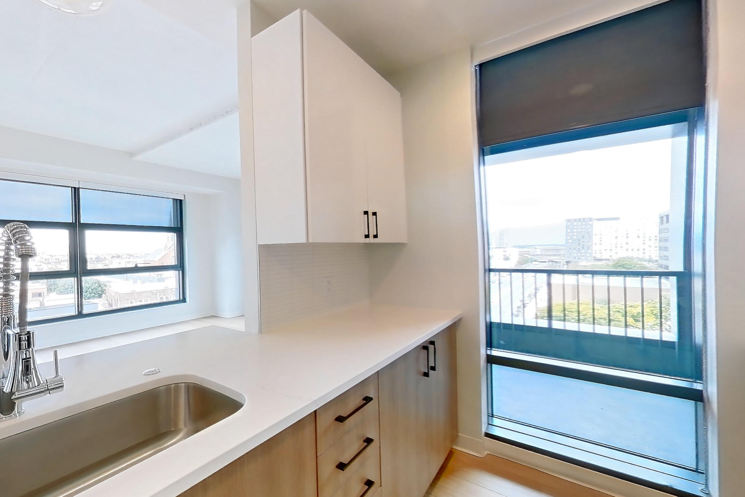 Kitchen with dishwasher, electric range, light countertops, light stone countertops, light wood-finish flooring, oven/range, refrigerator, stainless steel appliances, and water & ice dispenser, Apartment 0729 at The Alcott
