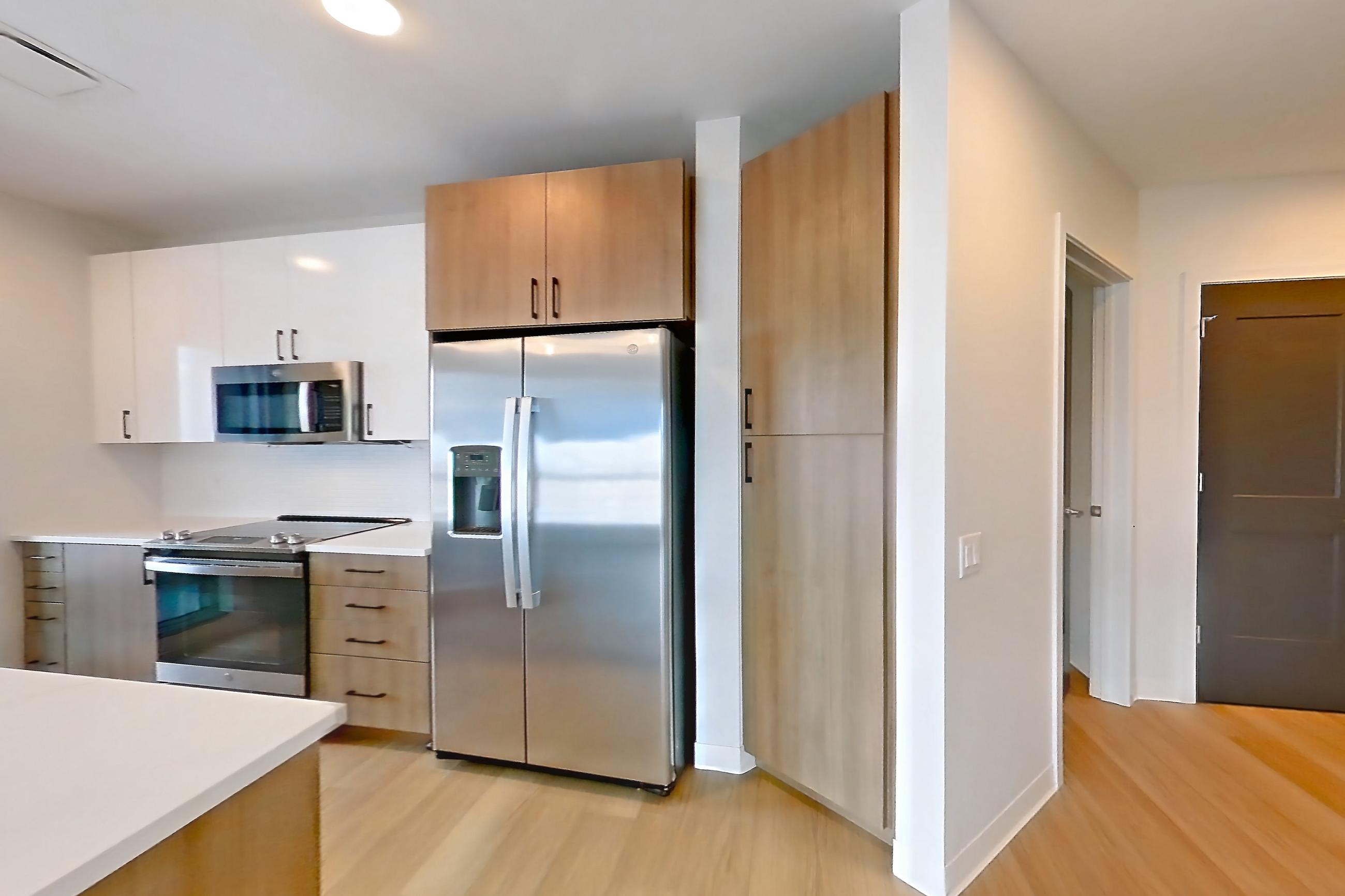 Living space with electric range, light countertops, light stone countertops, light wood-finish flooring, microwave, oven/range, refrigerator, stainless steel appliances, and water & ice dispenser, Apartment 0729 at The Alcott