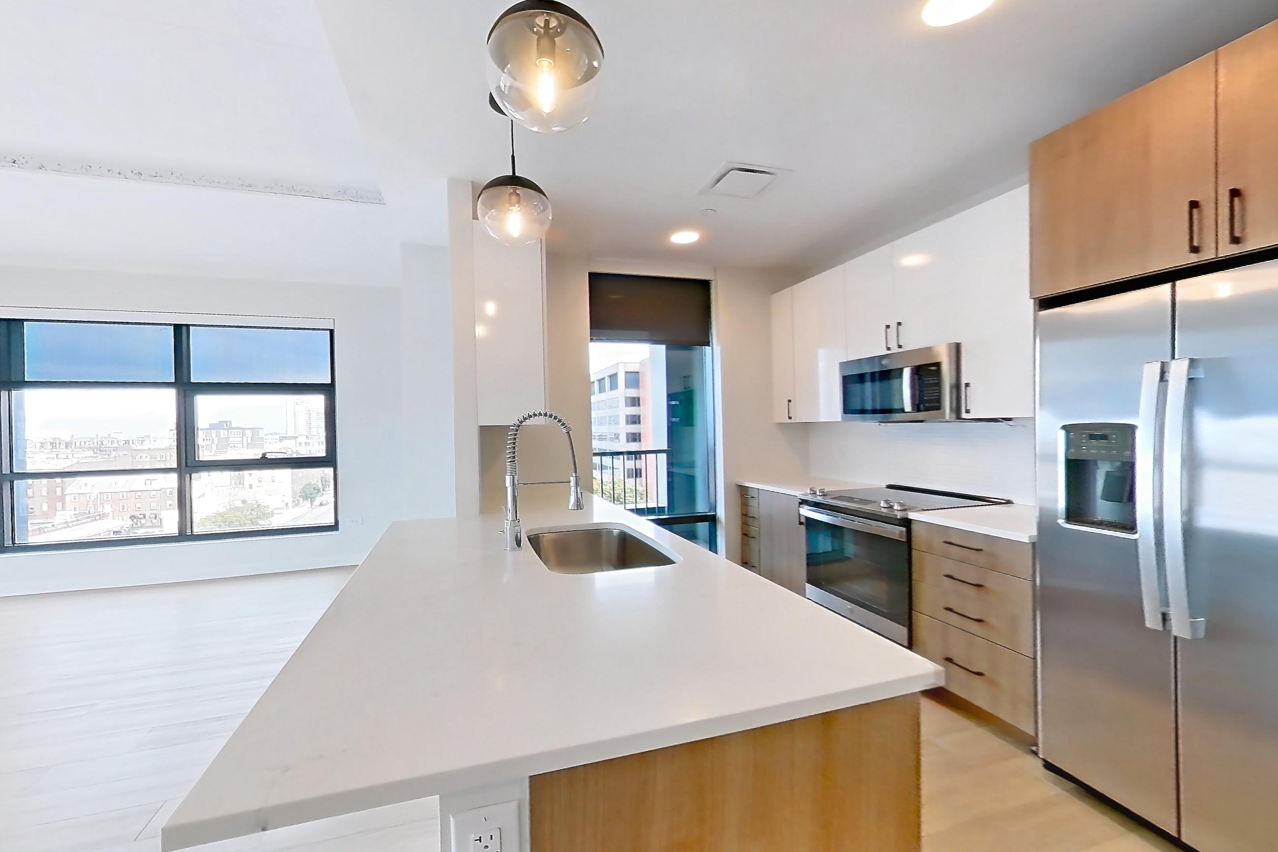 Living space with electric range, light countertops, light stone countertops, light wood-finish flooring, microwave, oven/range, refrigerator, stainless steel appliances, and water & ice dispenser, Apartment 0729 at The Alcott