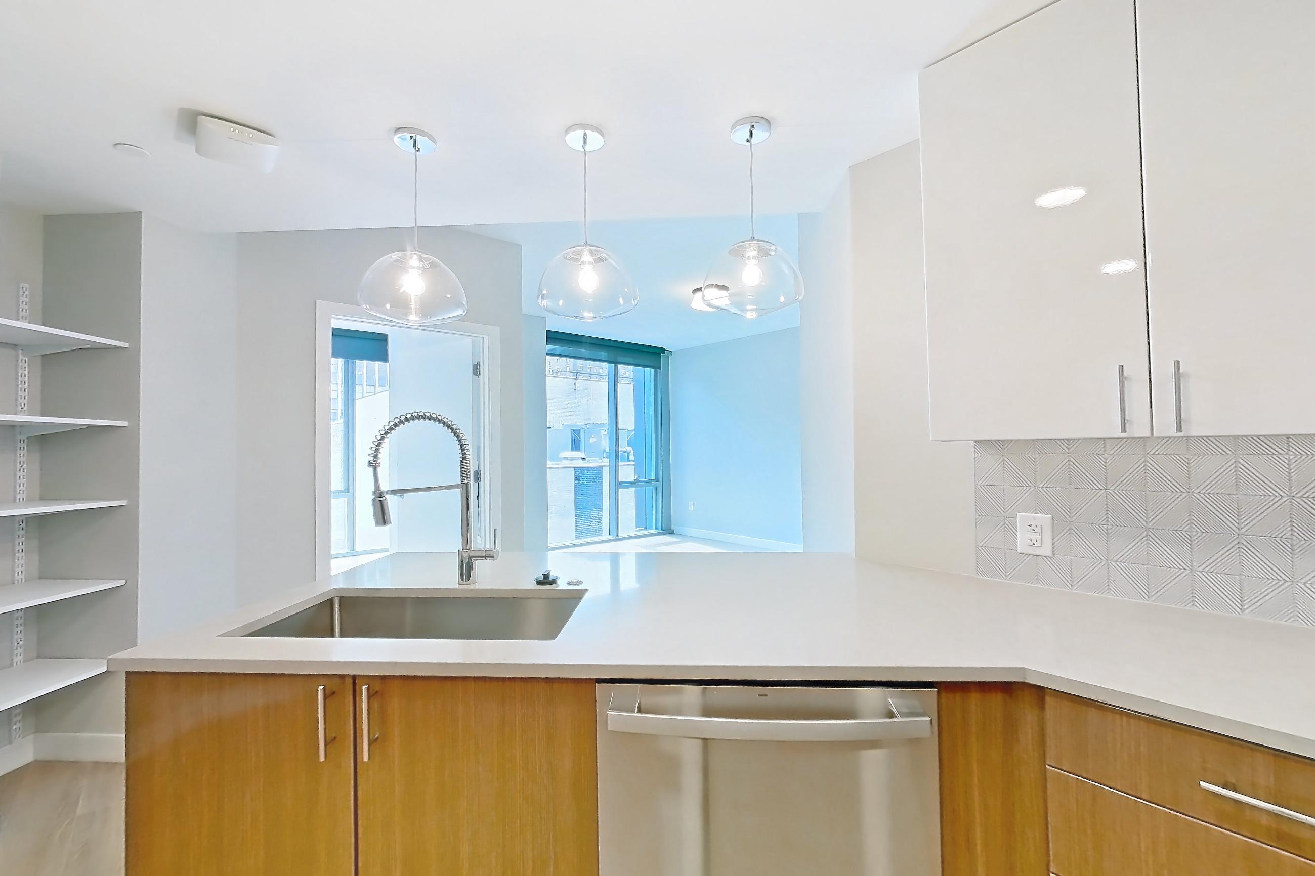 Kitchen with dishwasher, electric range, light countertops, light stone countertops, light wood-finish flooring, microwave, oven/range, refrigerator, stainless steel appliances, and water & ice dispenser, Apartment 0802 at Josephine