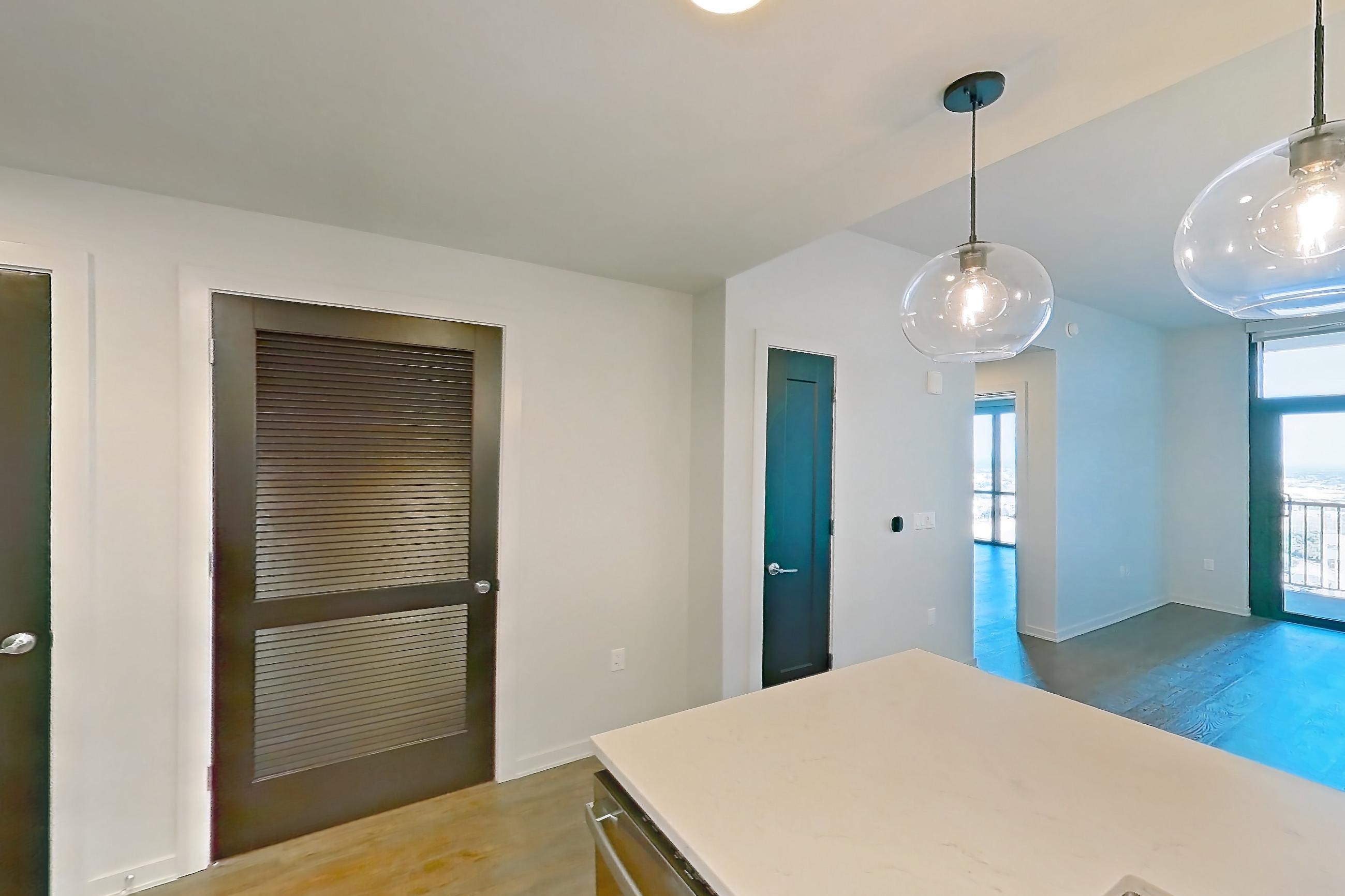 Kitchen with dishwasher, electric range, light countertops, light stone countertops, light wood-finish flooring, microwave, oven/range, range hood, and stainless steel appliances, Apartment 1917 at Deco 969