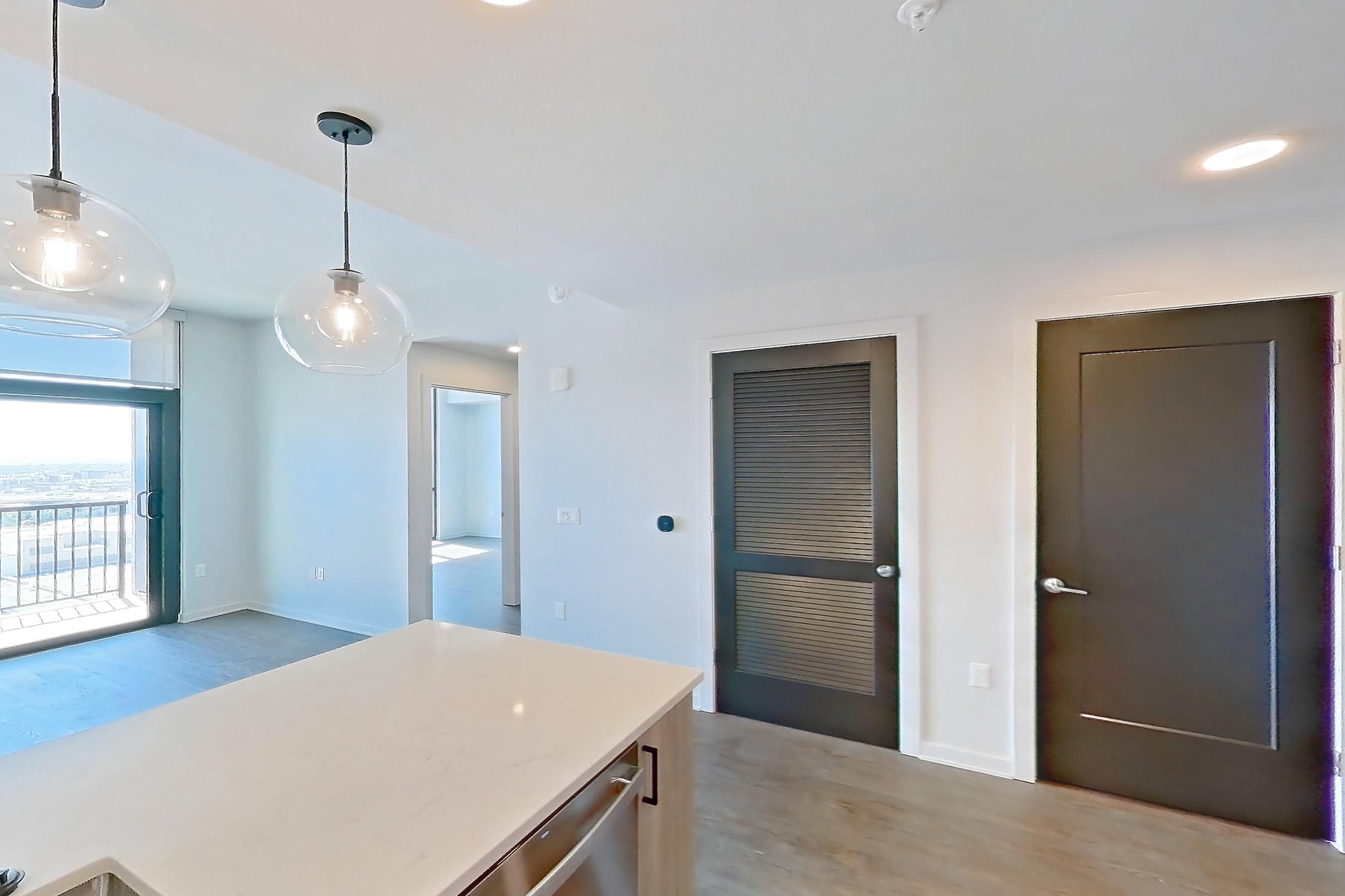 Kitchen with dishwasher, electric range, light countertops, light stone countertops, light wood-finish flooring, microwave, oven/range, and stainless steel appliances, Apartment 1910 at Deco 969