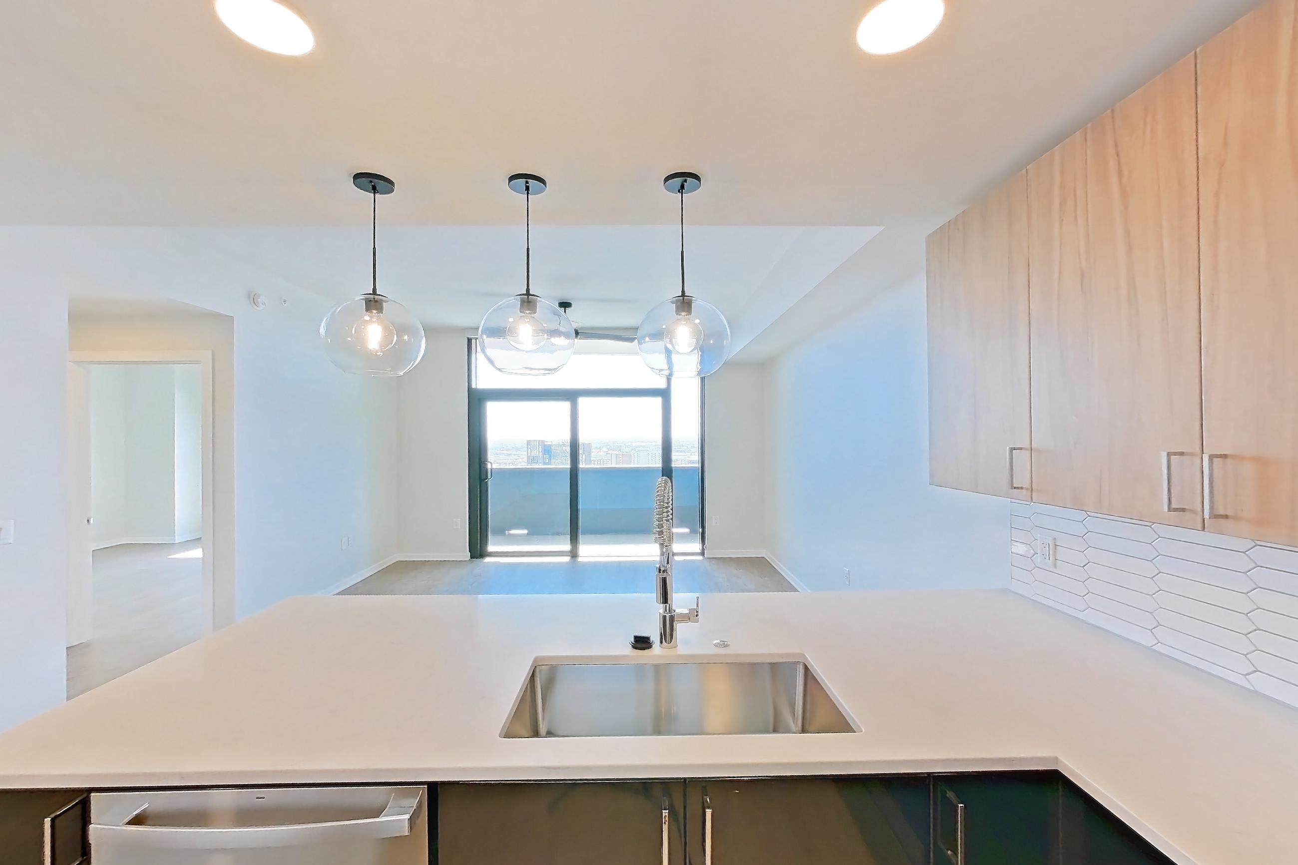 Kitchen with dishwasher, electric range, light countertops, light stone countertops, light wood-finish flooring, microwave, oven/range, and stainless steel appliances, Apartment 1806 at Deco 969