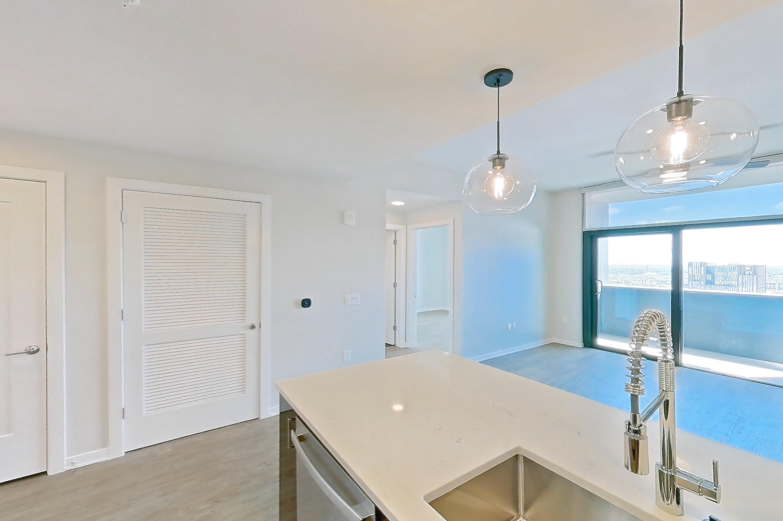 Kitchen with dishwasher, electric range, light countertops, light stone countertops, light wood-finish flooring, microwave, oven/range, range hood, and stainless steel appliances, Apartment 1608 at Deco 969