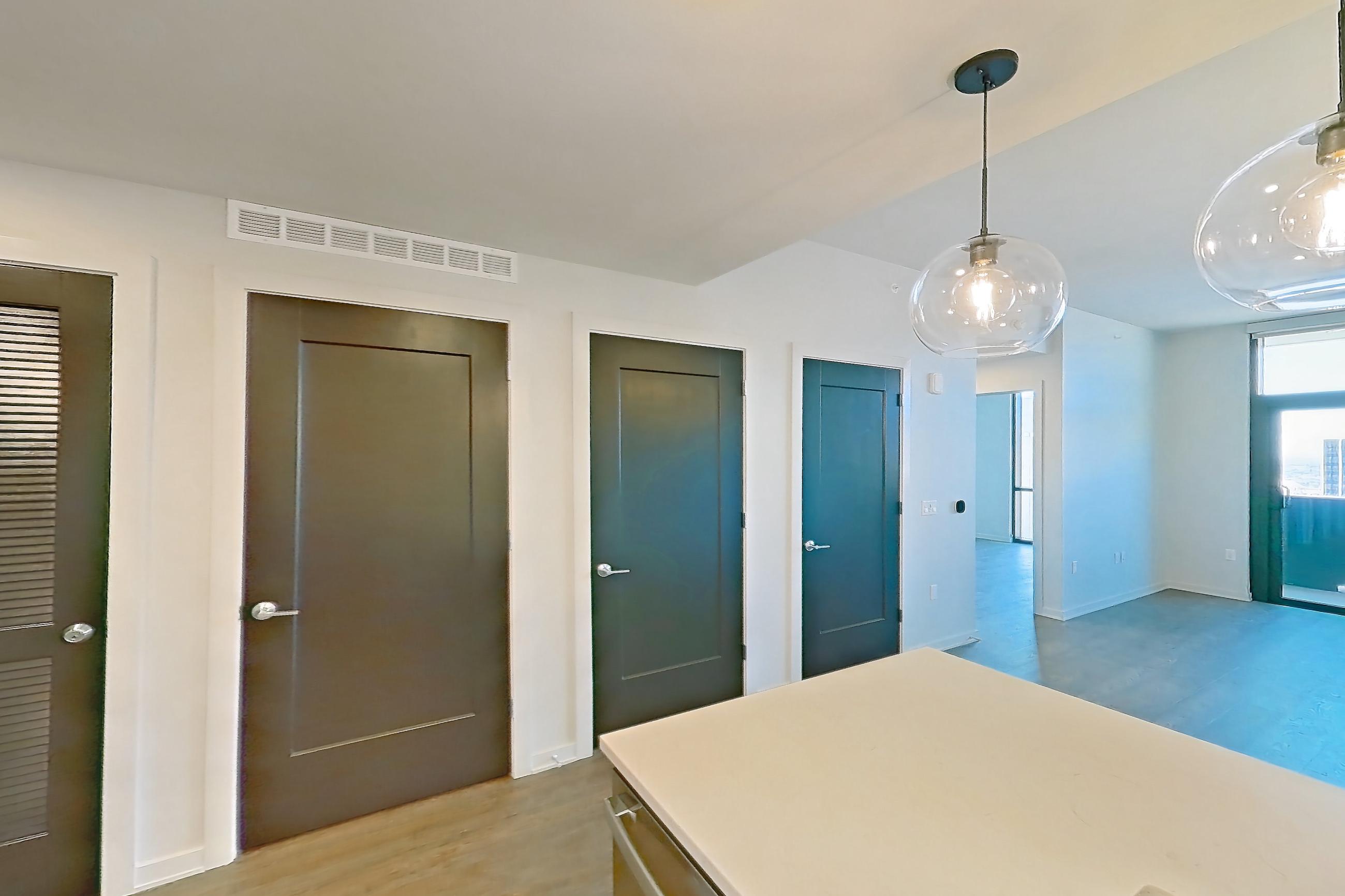 Kitchen with dishwasher, electric range, light countertops, light stone countertops, light wood-finish flooring, microwave, oven/range, range hood, and stainless steel appliances, Apartment 1918 at Deco 969