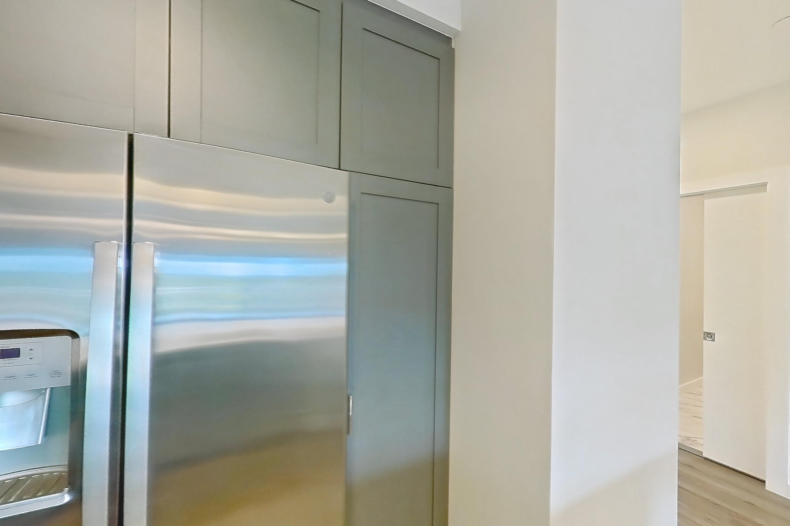 Kitchen with dishwasher, gas range, light countertops, light stone countertops, light wood-finish flooring, microwave, oven/range, refrigerator, stainless steel appliances, and water & ice dispenser, Apartment S306 at Carlow Wind Watch