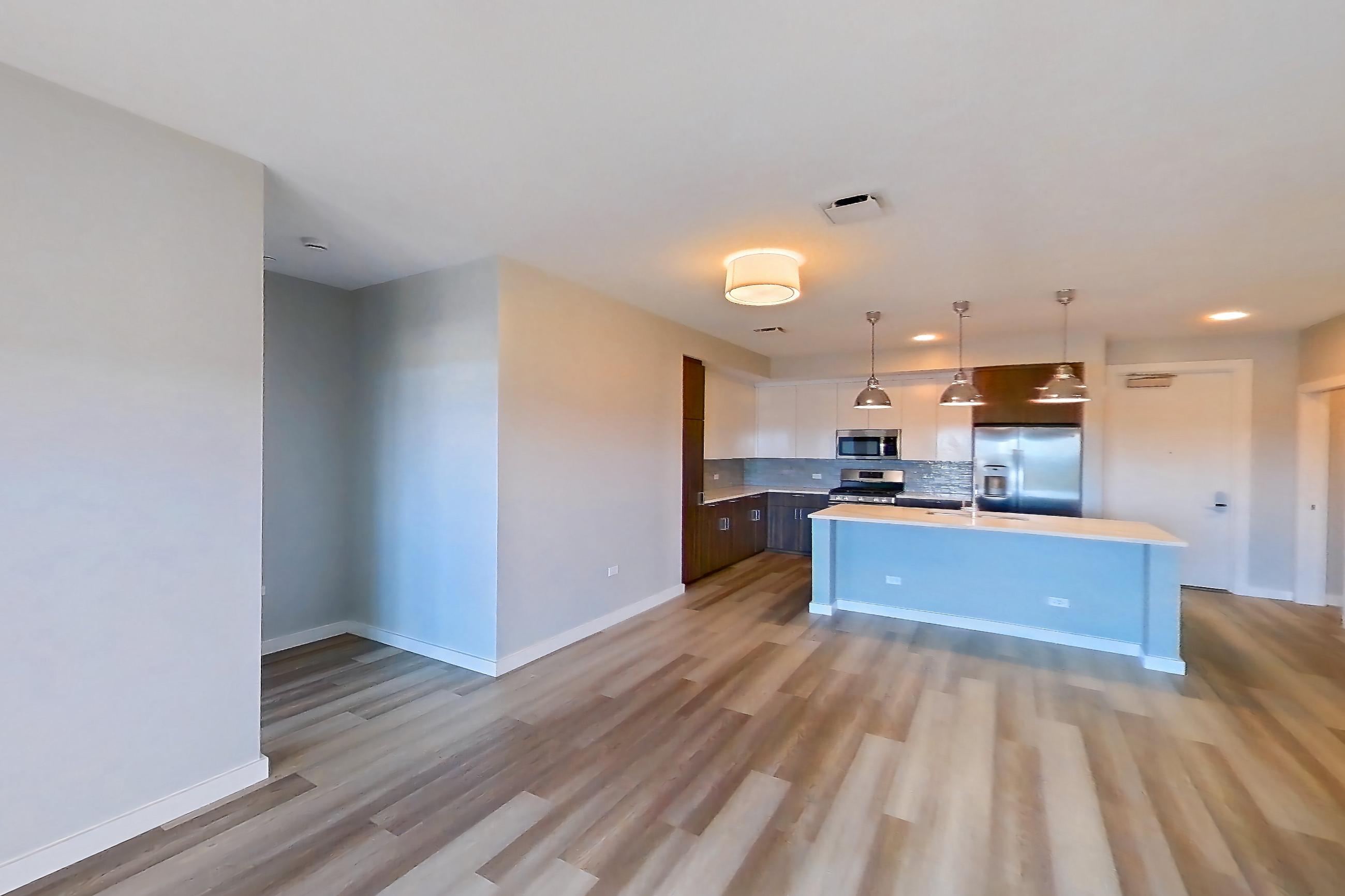 Living space with kitchen island, light countertops, light wood-finish flooring, oven/range, and stainless steel appliances, Apartment N201 at Carlow Wind Watch