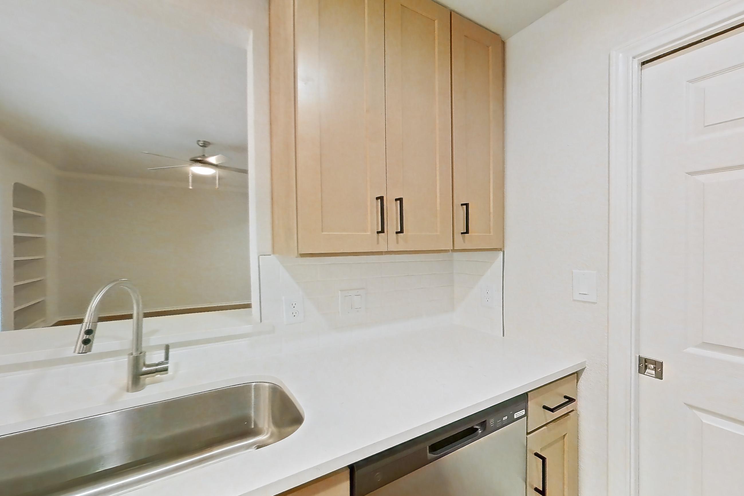 Kitchen with dishwasher, gas range, light countertops, light stone countertops, light wood-finish flooring, microwave, oven/range, refrigerator, and stainless steel appliances, Apartment 1805 at Marquis at Caprock Canyon