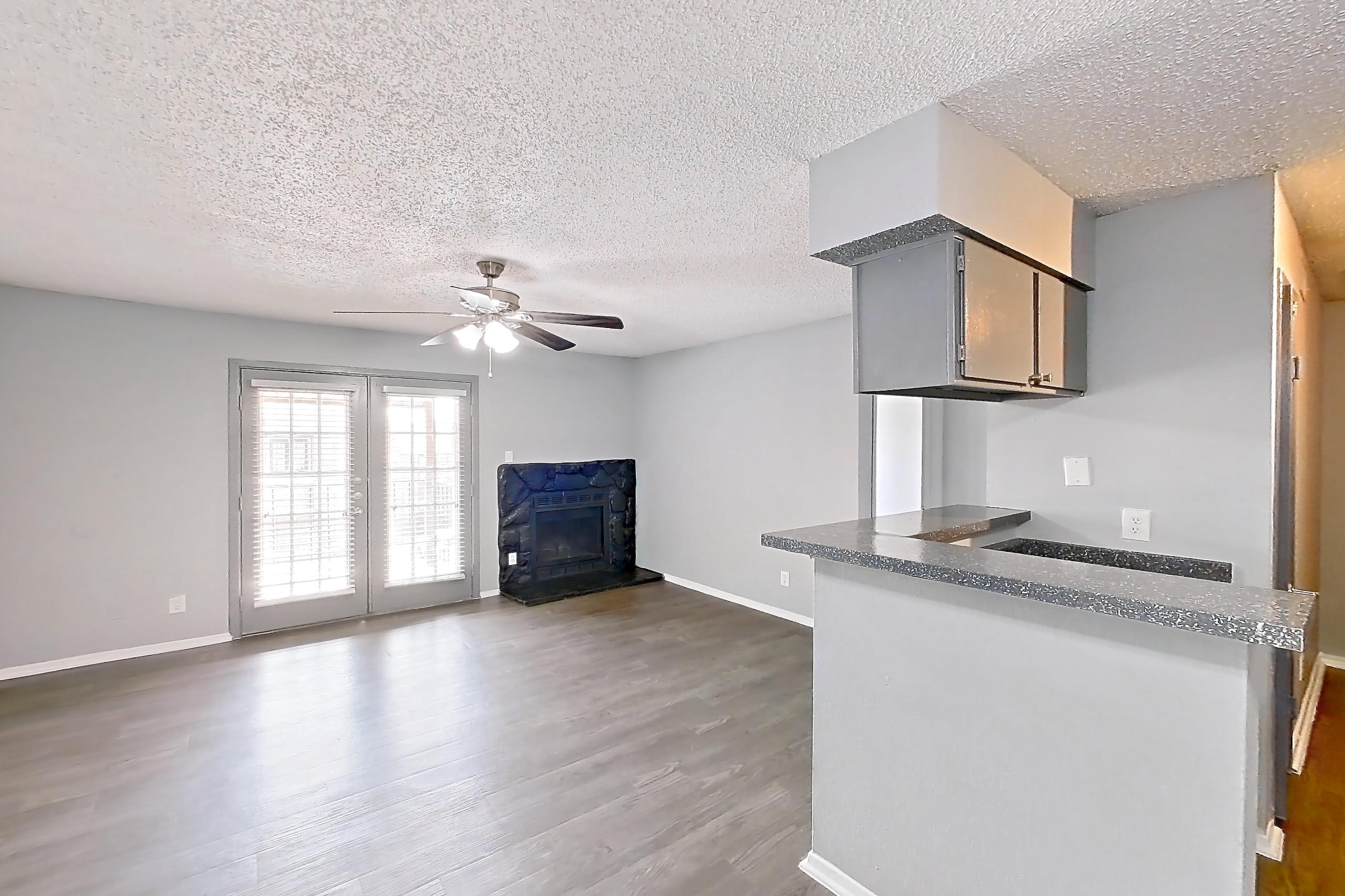 Dining room with dark countertops, dark wood-finish flooring, dishwasher, electric range, fireplace, microwave, oven/range, stainless steel appliances, and stone fireplace, Apartment 106 at Marine Creek Apartments