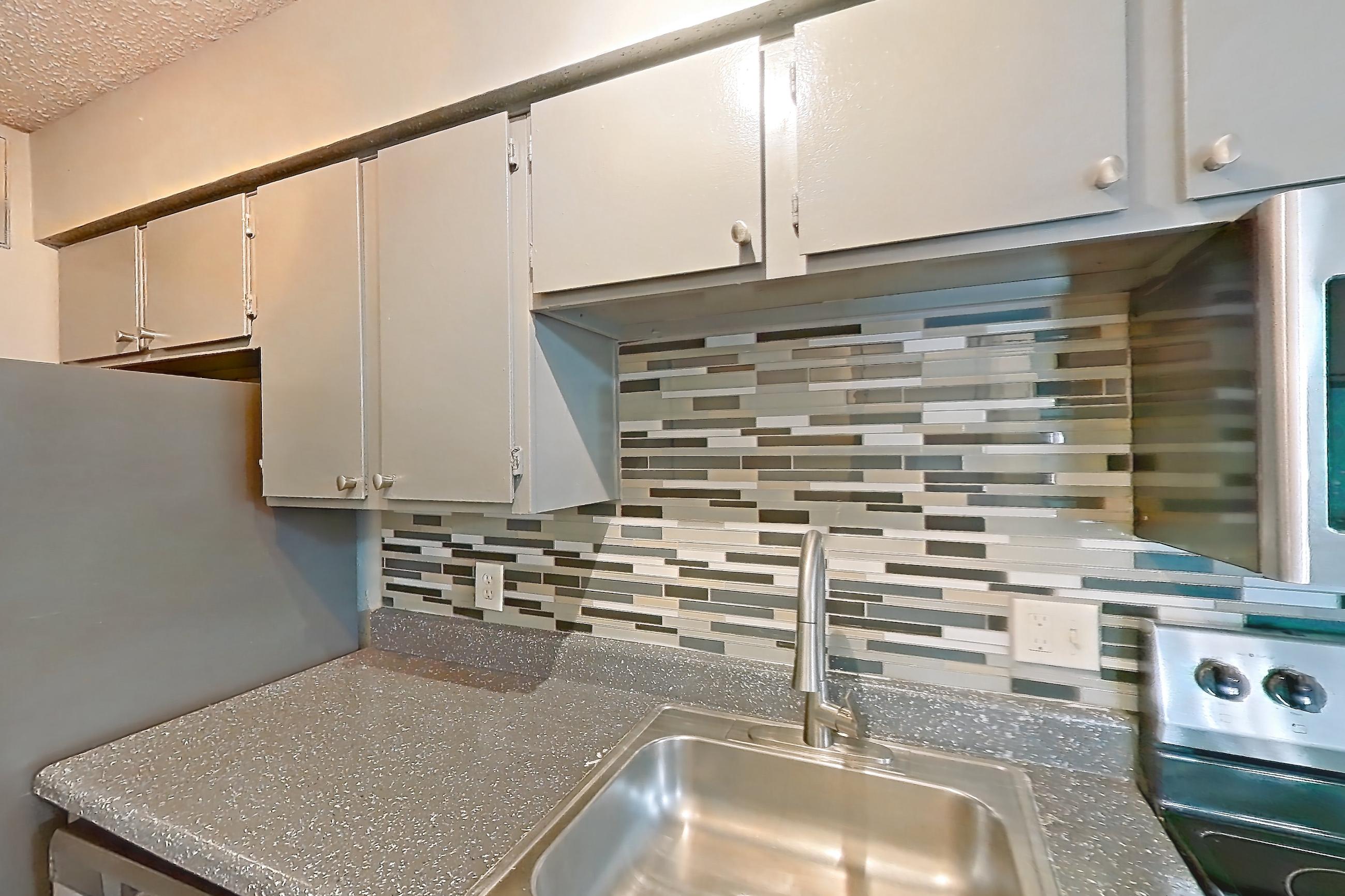 Kitchen with dark countertops, electric range, light countertops, light wood-finish flooring, microwave, oven/range, and stainless steel appliances, Apartment 106 at Marine Creek Apartments