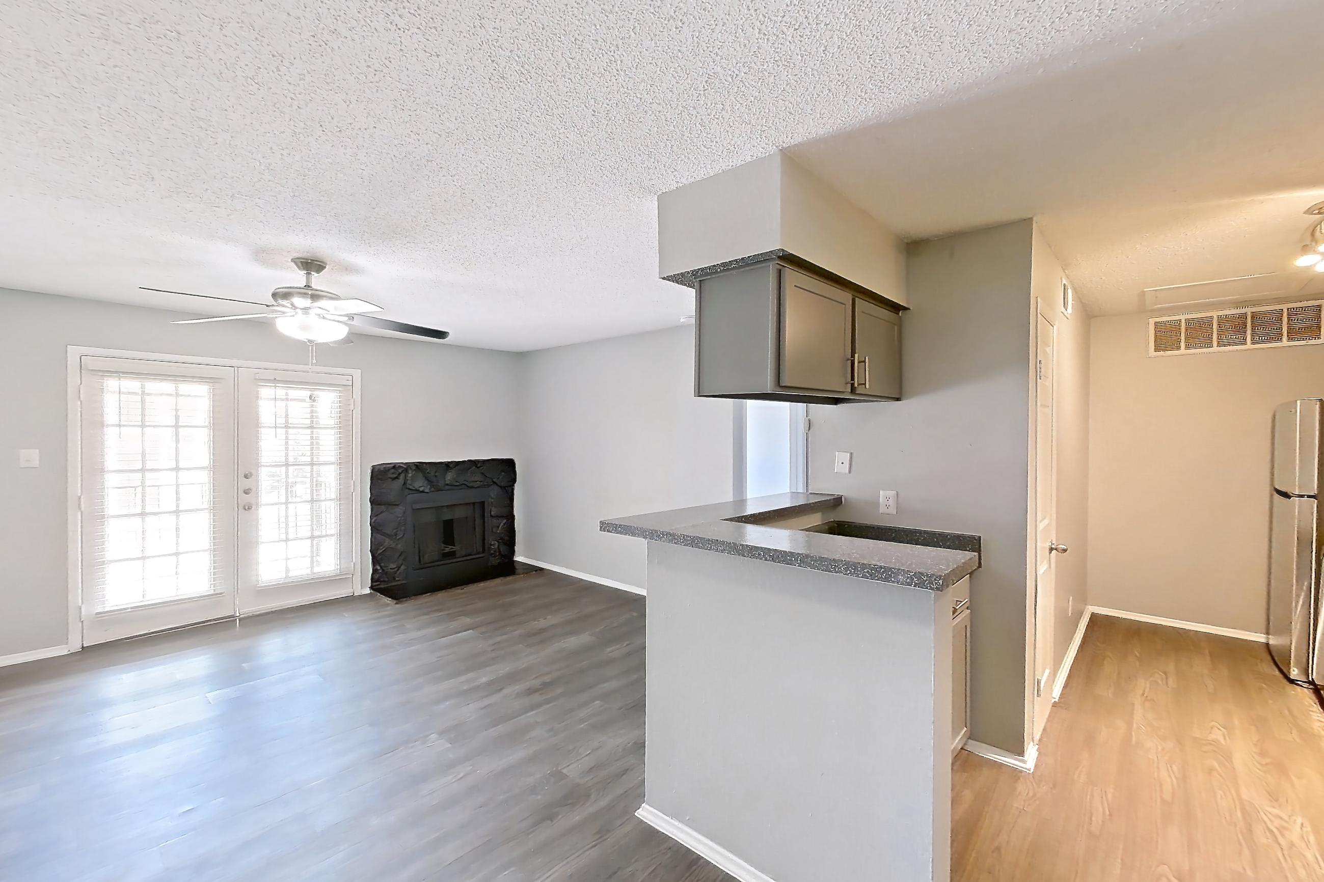 Dining room with dark countertops, dark wood-finish flooring, electric range, fireplace, light countertops, oven/range, refrigerator, stainless steel appliances, stone fireplace, and white appliances, Apartment 508 at Marine Creek Apartments
