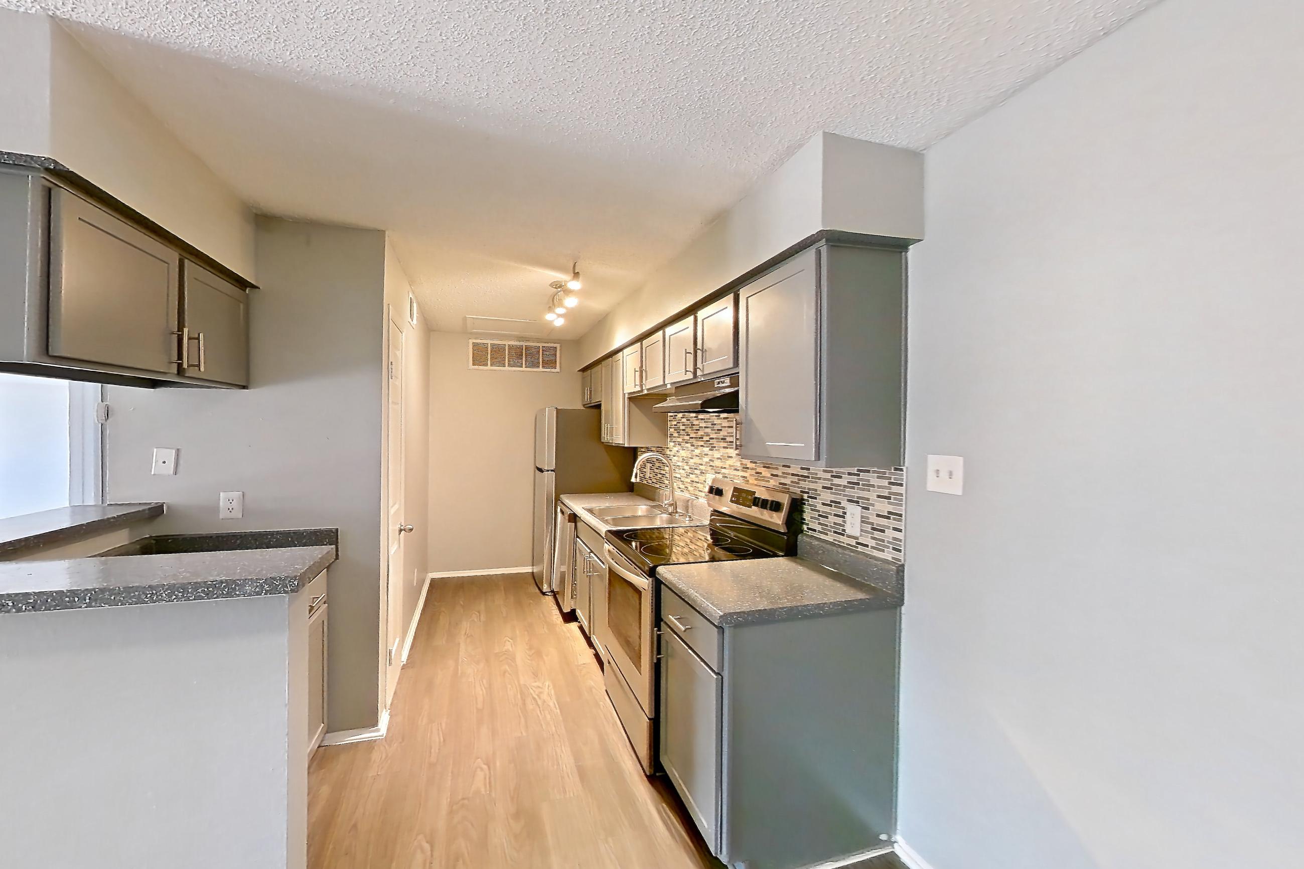 Dining room with dark countertops, dark wood-finish flooring, electric range, fireplace, light countertops, oven/range, refrigerator, stainless steel appliances, stone fireplace, and white appliances, Apartment 508 at Marine Creek Apartments