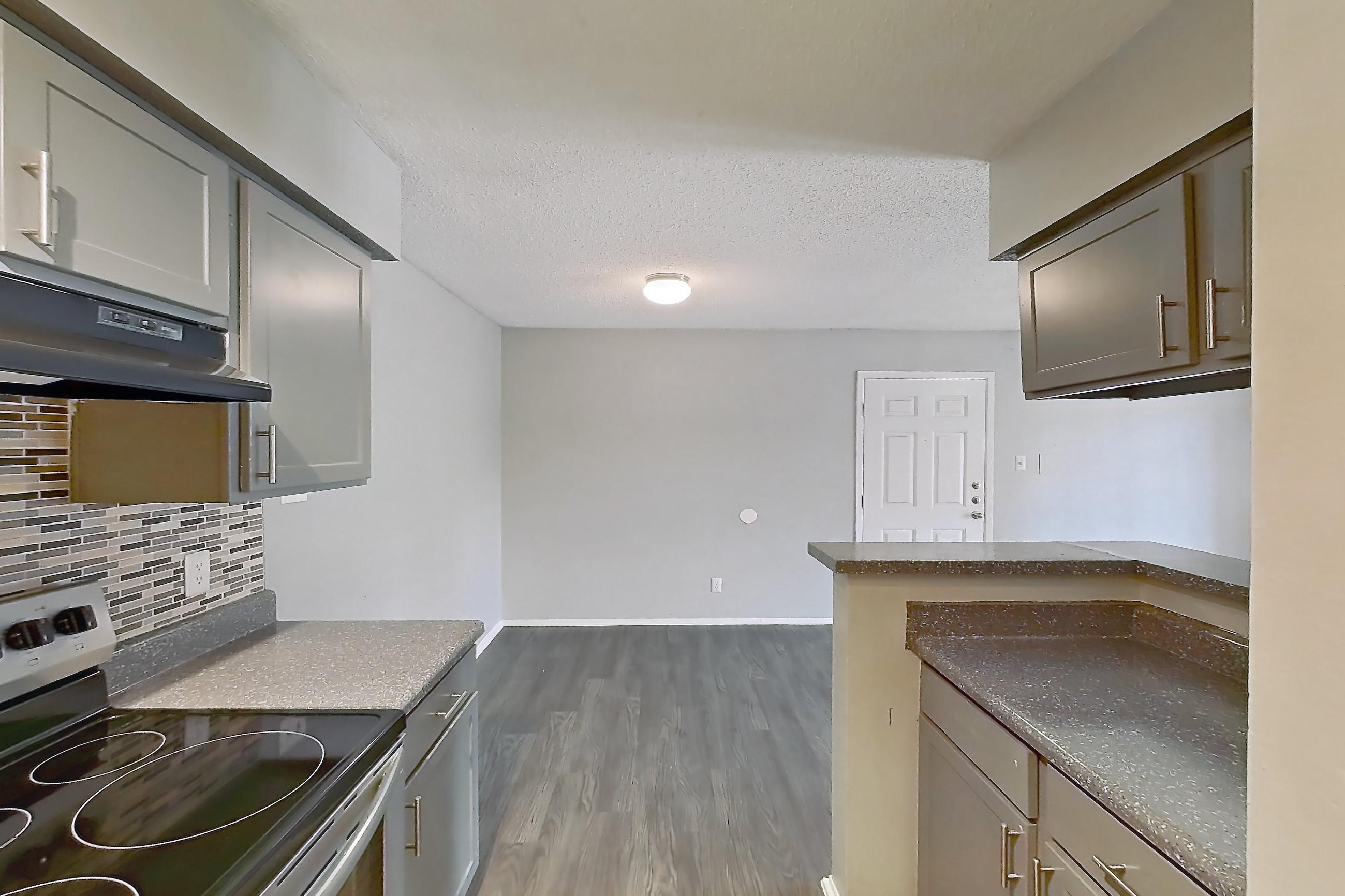 Kitchen with dark countertops, electric range, light countertops, light wood-finish flooring, oven/range, and stainless steel appliances, Apartment 508 at Marine Creek Apartments