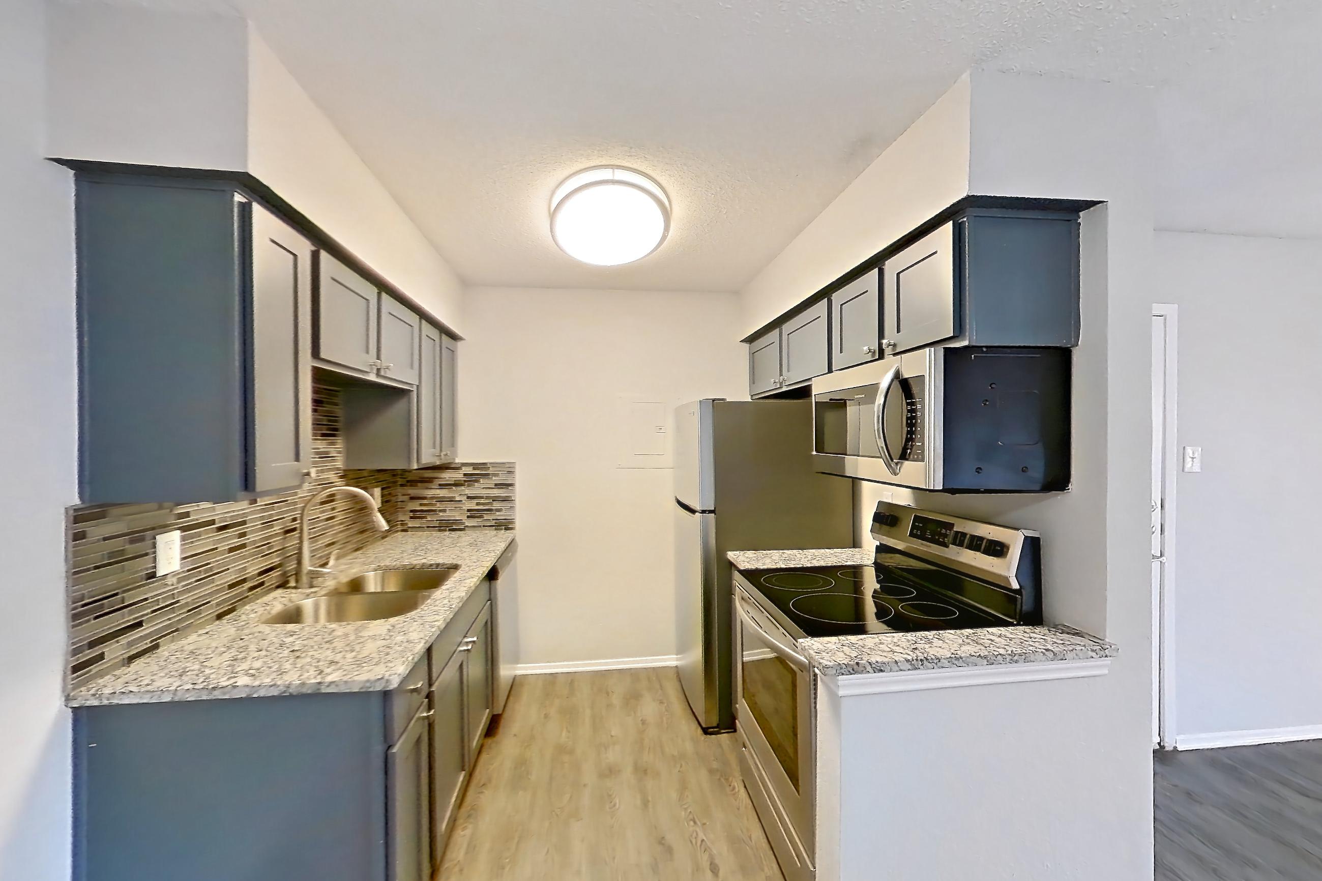 Dining room with dark wood-finish flooring, dishwasher, electric range, light stone countertops, oven/range, refrigerator, and stainless steel appliances, Apartment 603 at Marine Creek Apartments