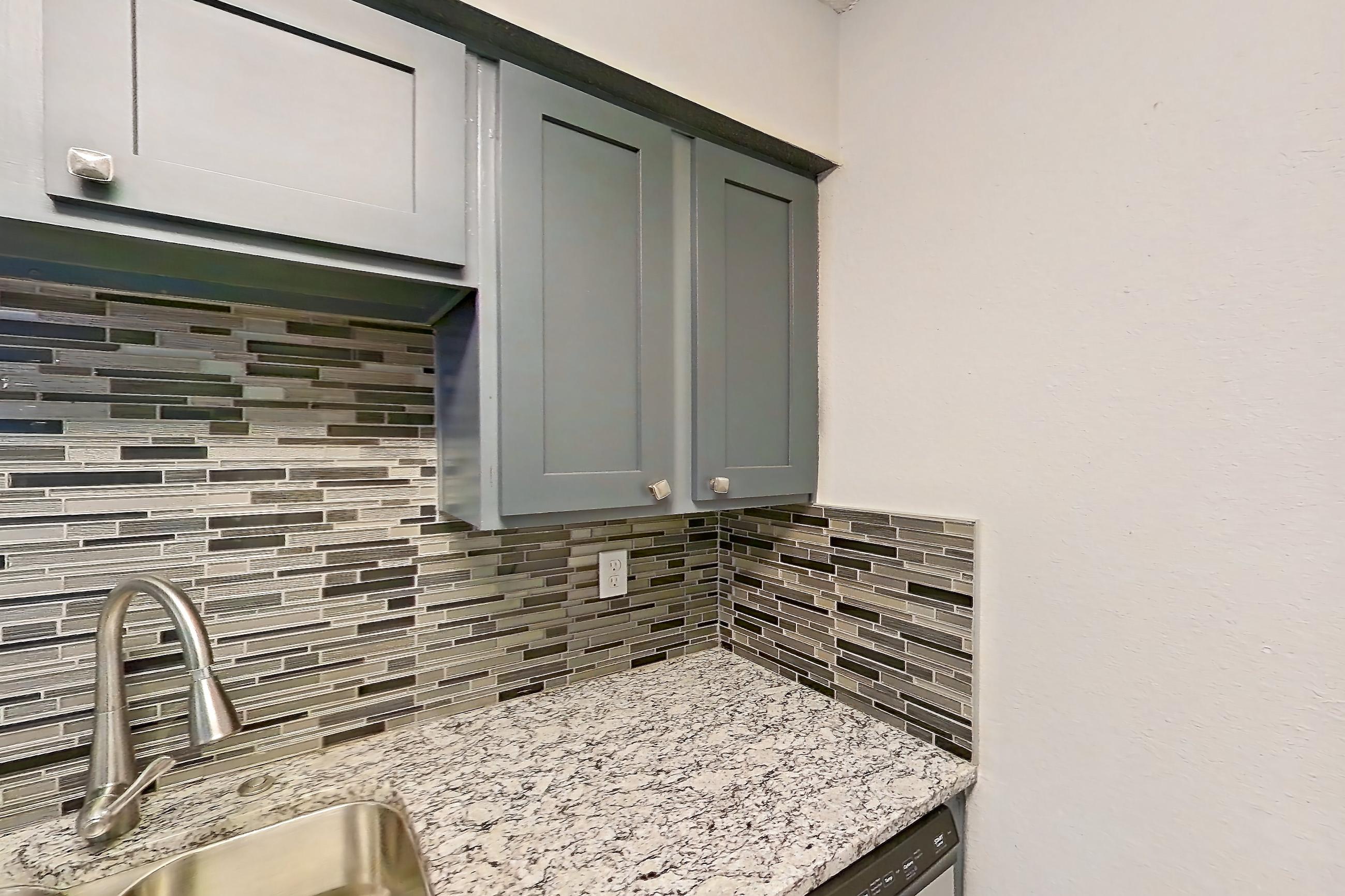 Kitchen with dishwasher, electric range, light stone countertops, light wood-finish flooring, oven/range, refrigerator, and stainless steel appliances, Apartment 603 at Marine Creek Apartments