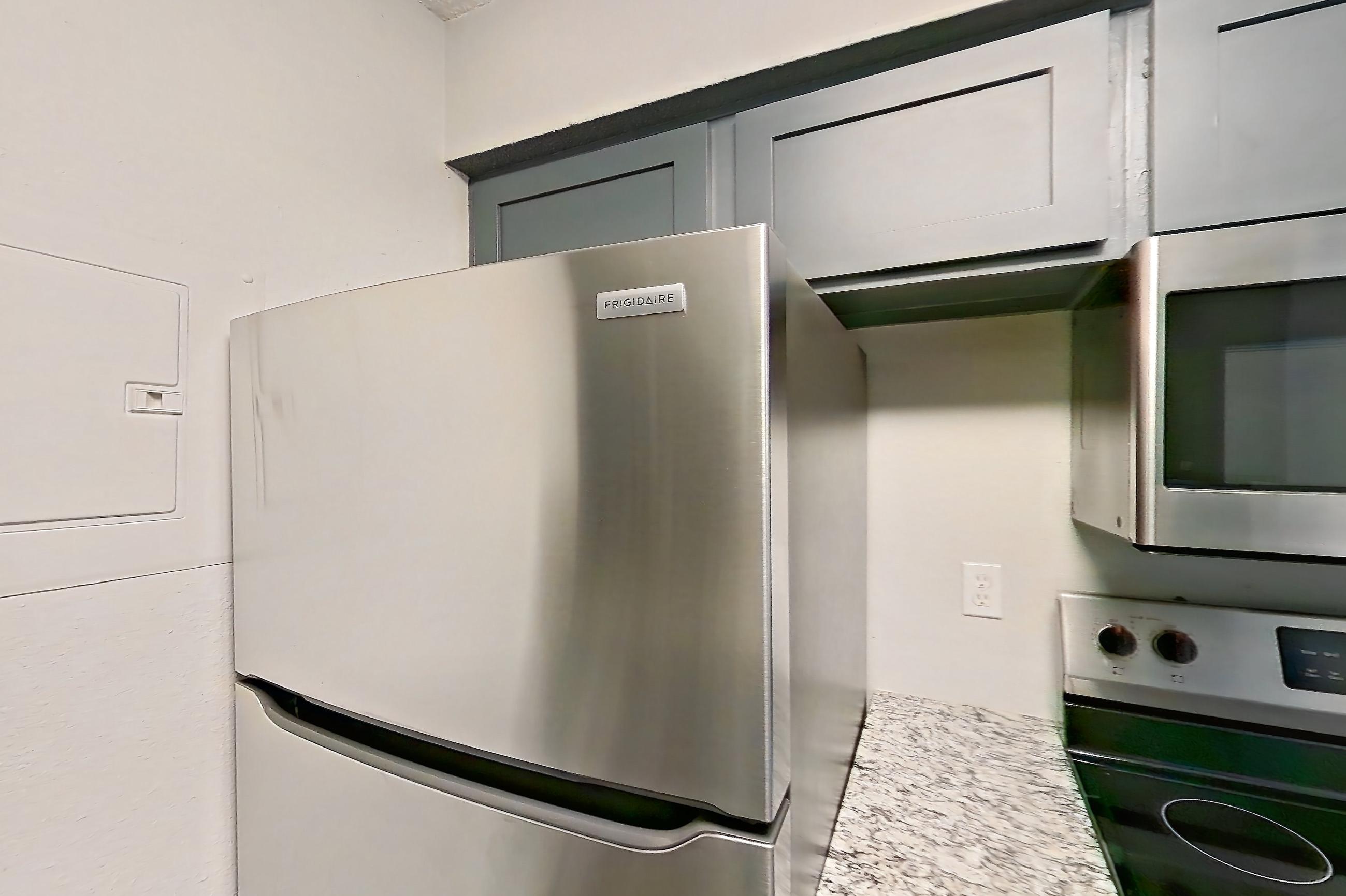 Kitchen with dishwasher, electric range, light stone countertops, light wood-finish flooring, oven/range, refrigerator, and stainless steel appliances, Apartment 603 at Marine Creek Apartments