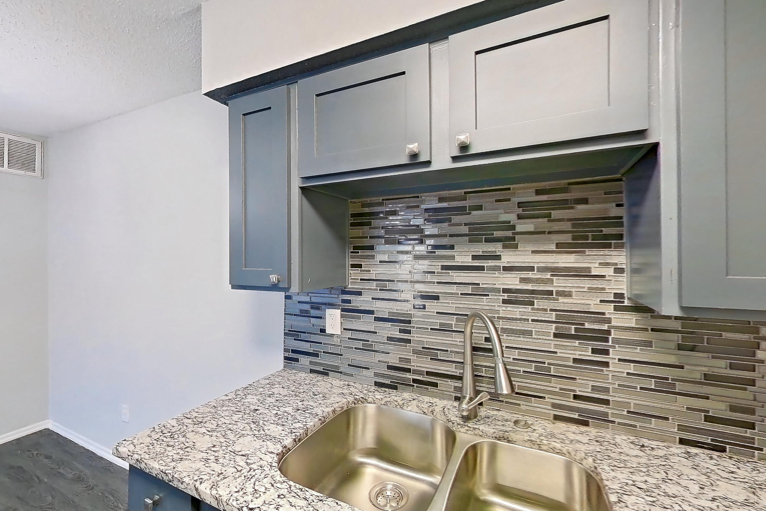 Kitchen with dishwasher, electric range, light stone countertops, light wood-finish flooring, oven/range, refrigerator, and stainless steel appliances, Apartment 603 at Marine Creek Apartments