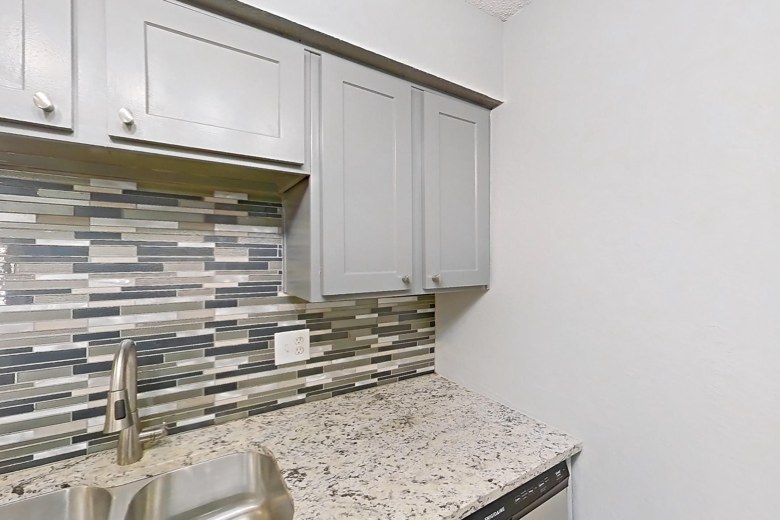 Kitchen with dishwasher, electric range, light countertops, light stone countertops, light wood-finish flooring, microwave, oven/range, refrigerator, and stainless steel appliances, Apartment 608 at Marine Creek Apartments